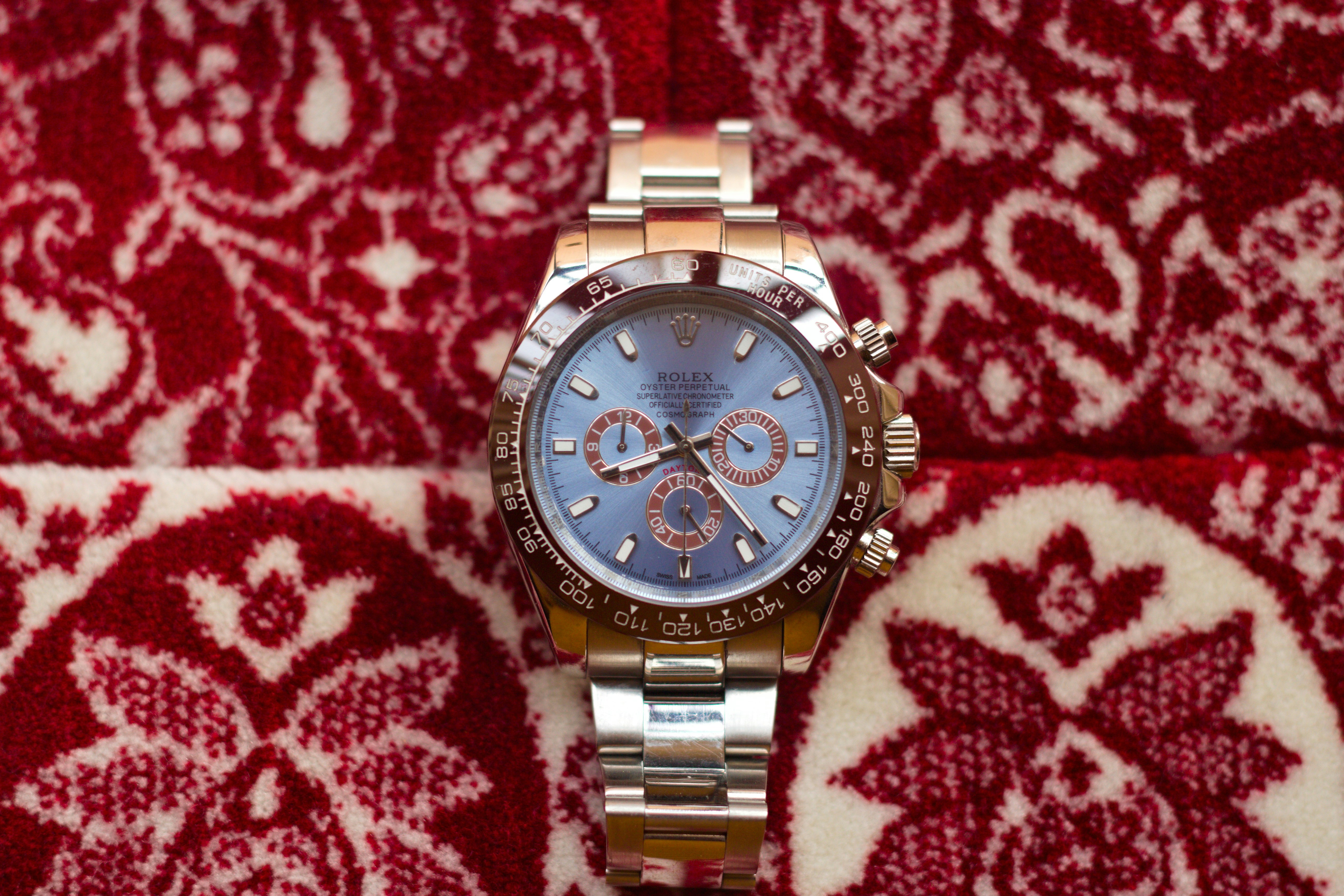 A close-up of a luxury watch on a patterned rug.