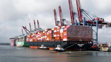 Large container ships docked at a busy port with cranes.