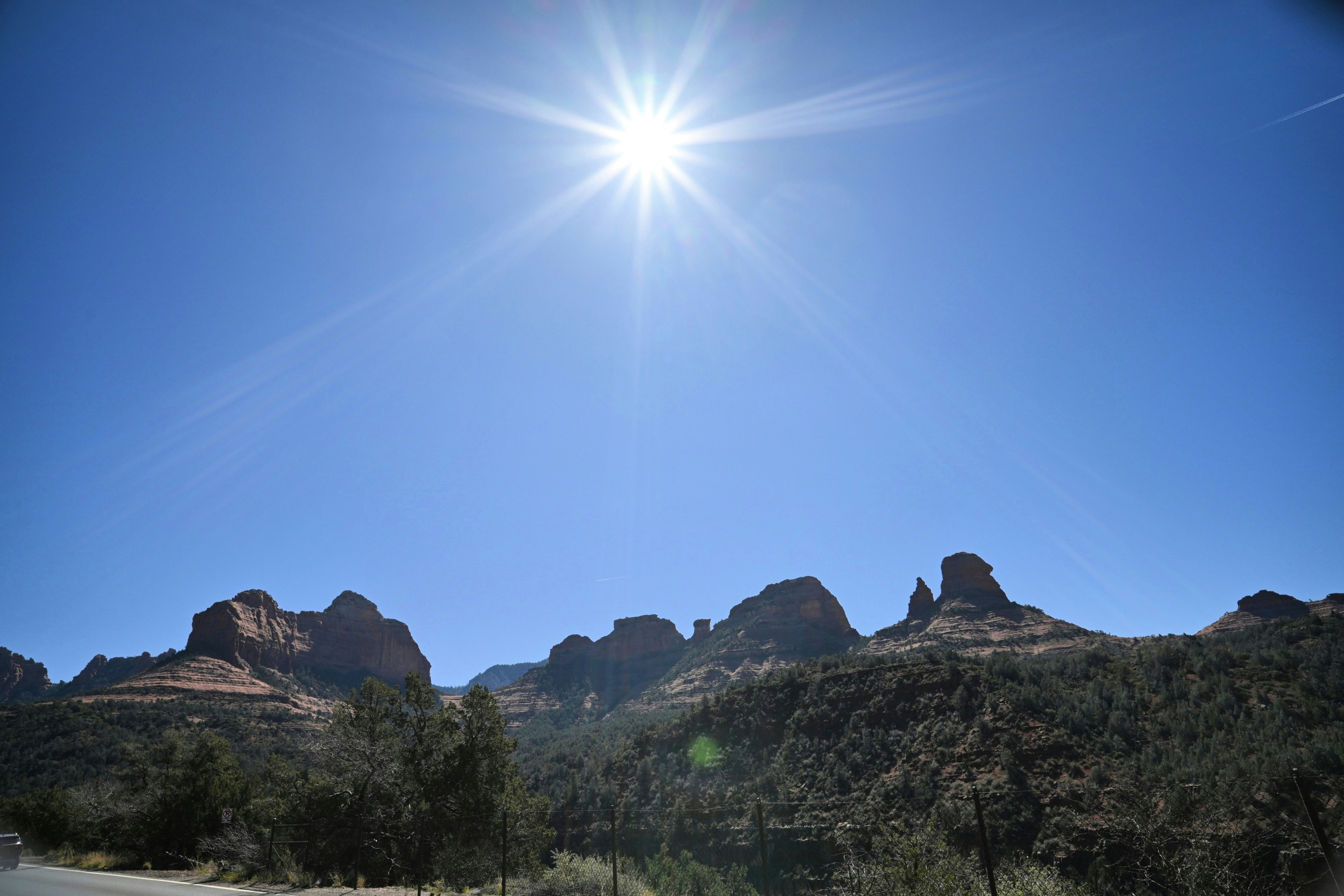 Bright sun shines over rocky desert landscape.