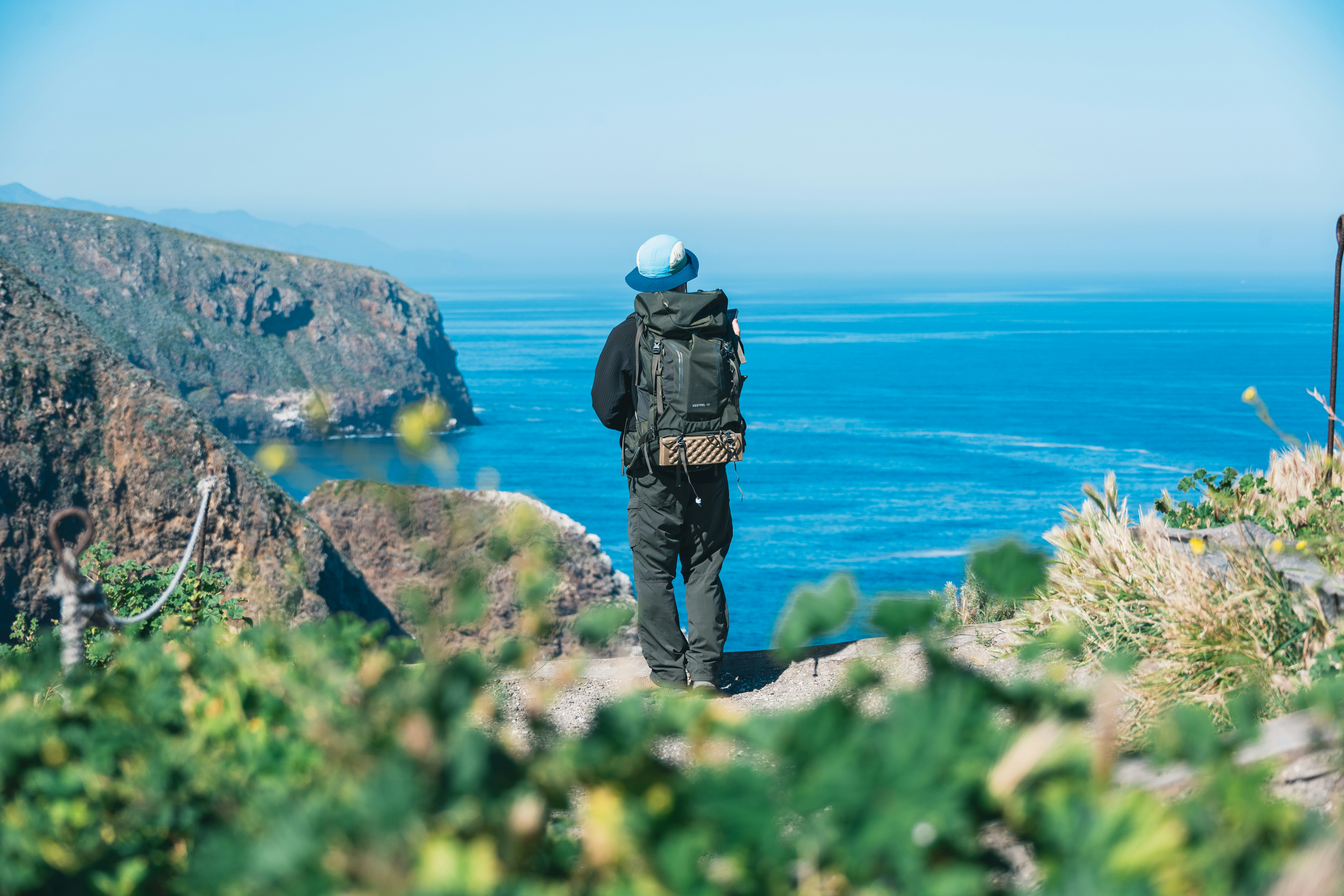 Caminhante com mochila com vista para o oceano de um penhasco.