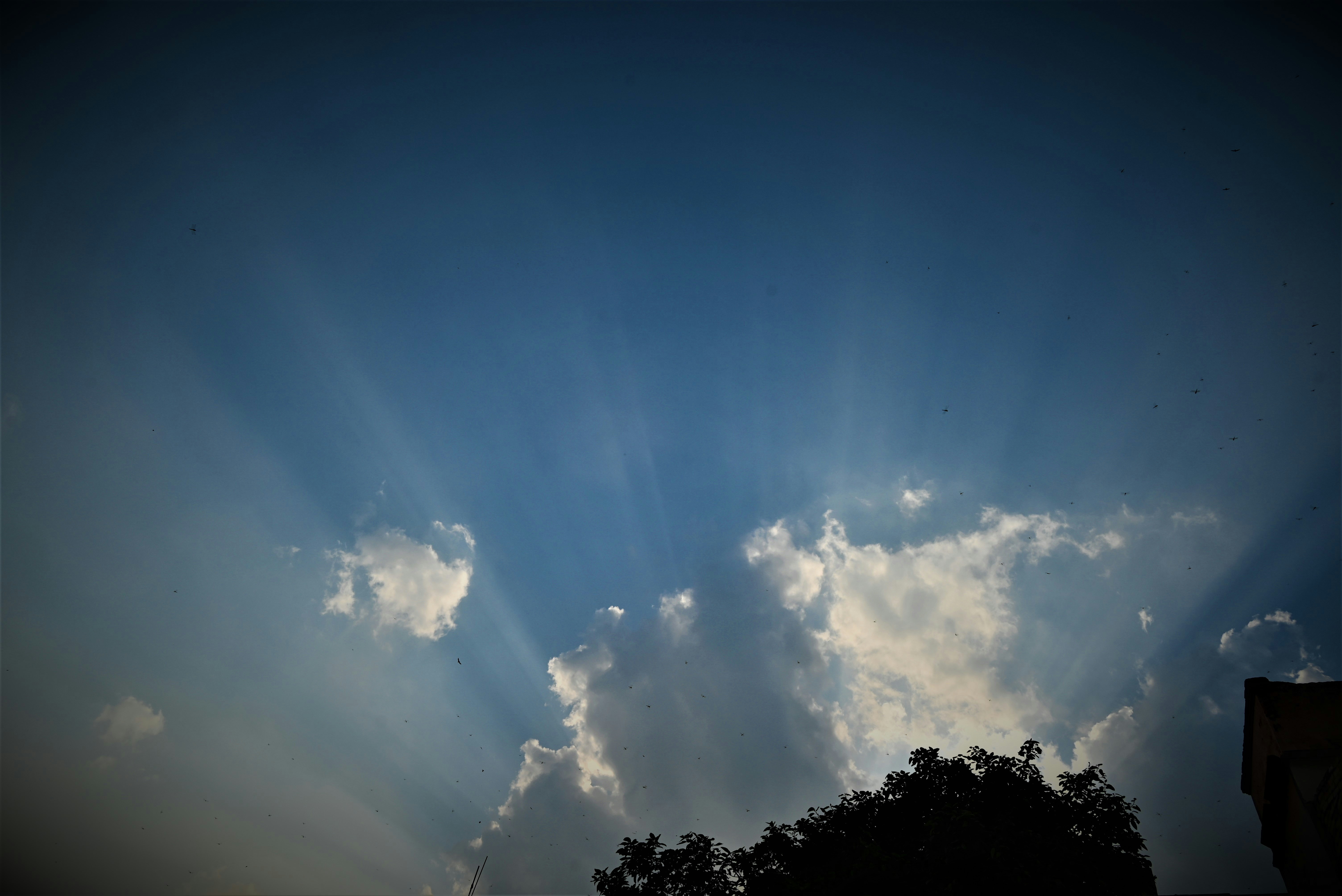 I raggi del sole attraversano le nuvole in un cielo azzurro.