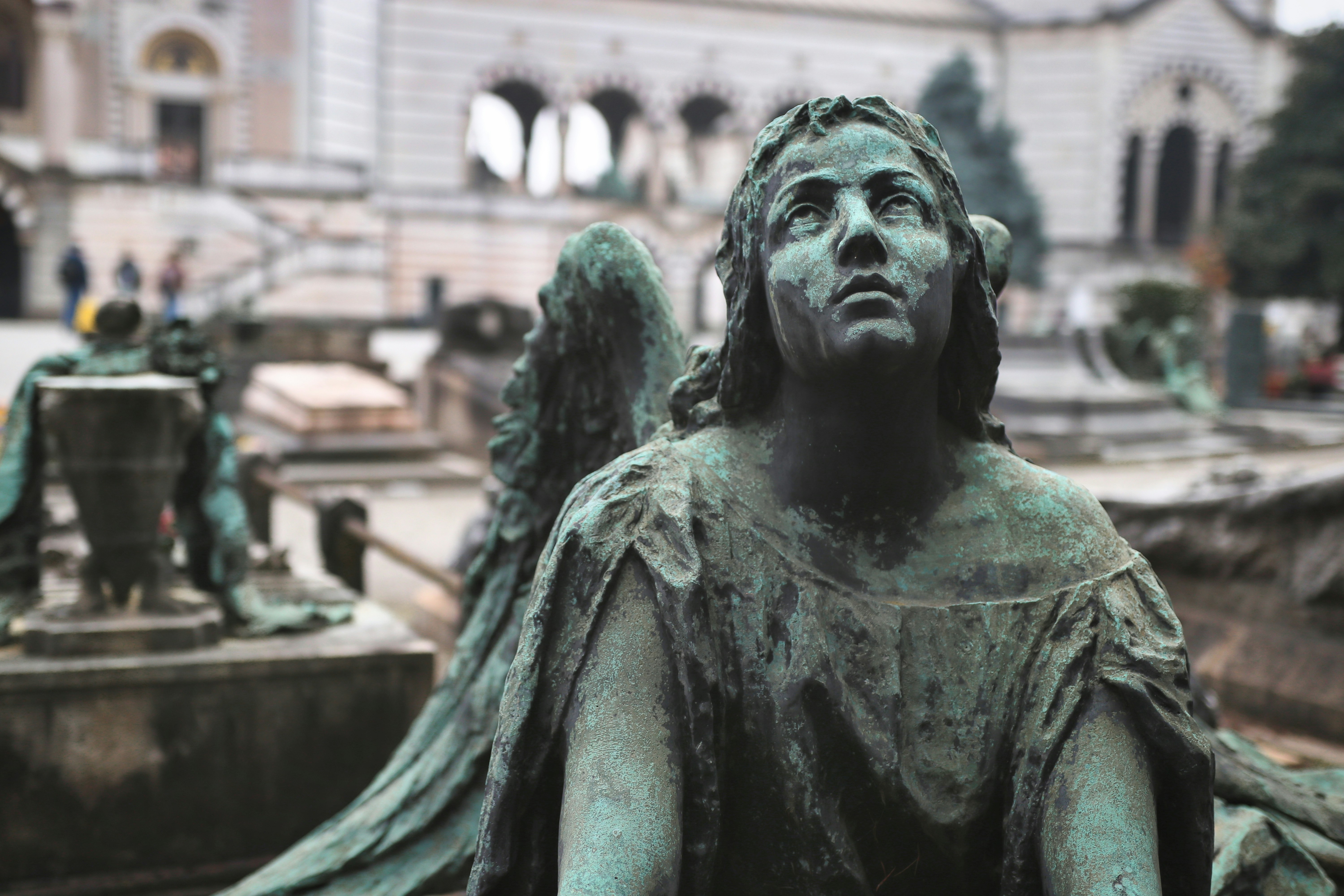 A weathered bronze statue of an angel in a cemetery.