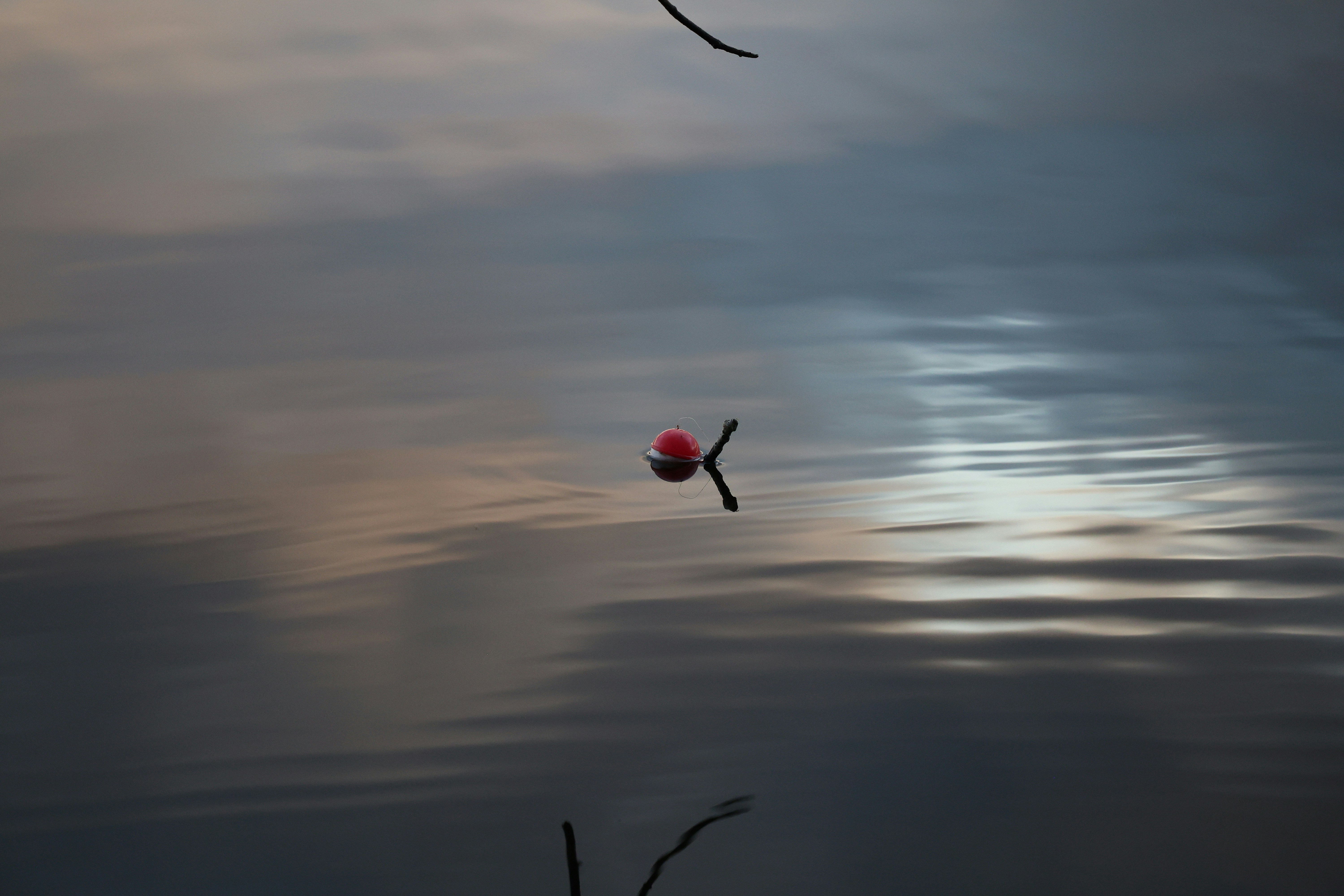 Red fishing bobber floating on calm water