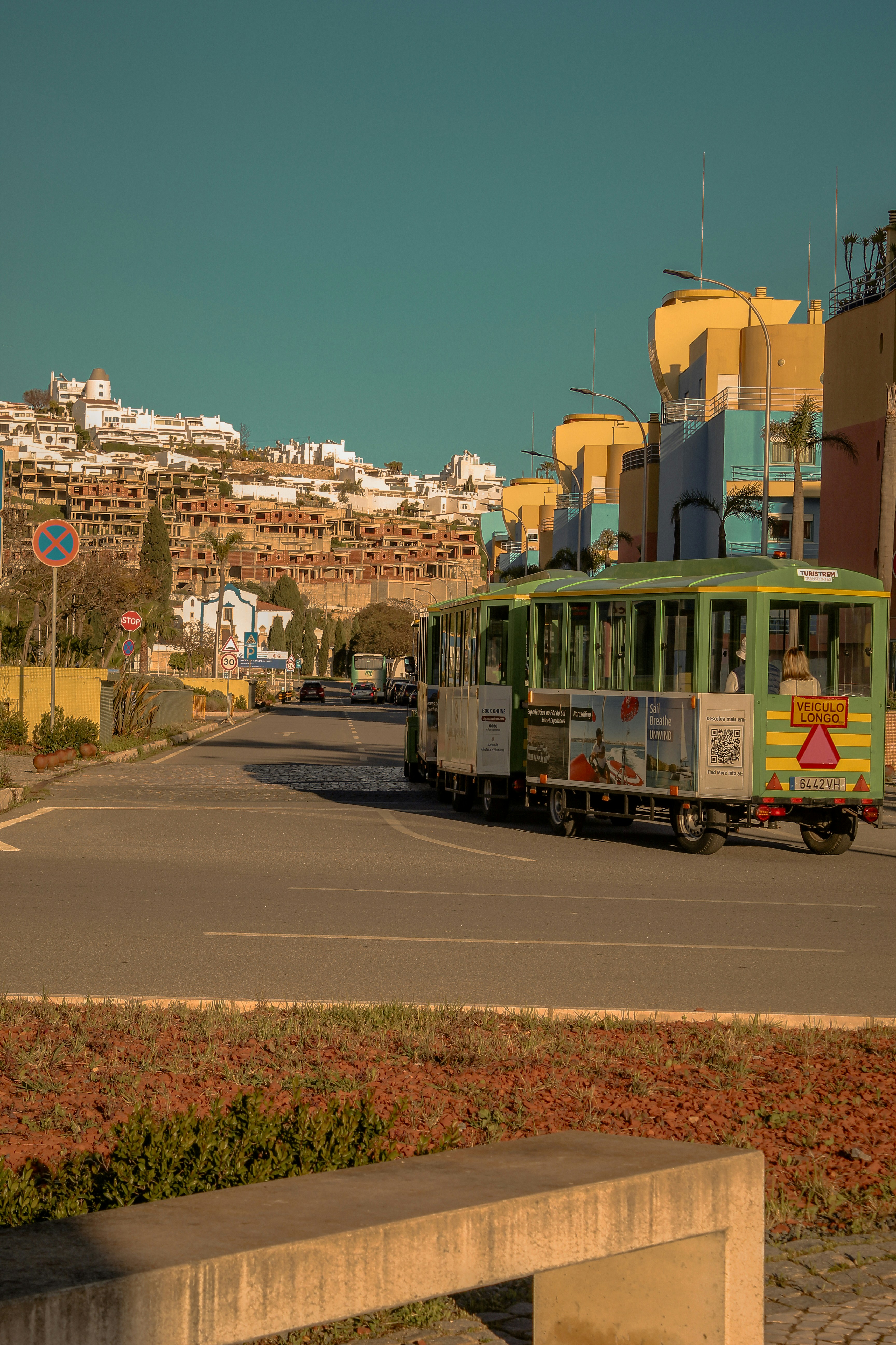 Train touristique vert dans une rue aux bâtiments colorés.