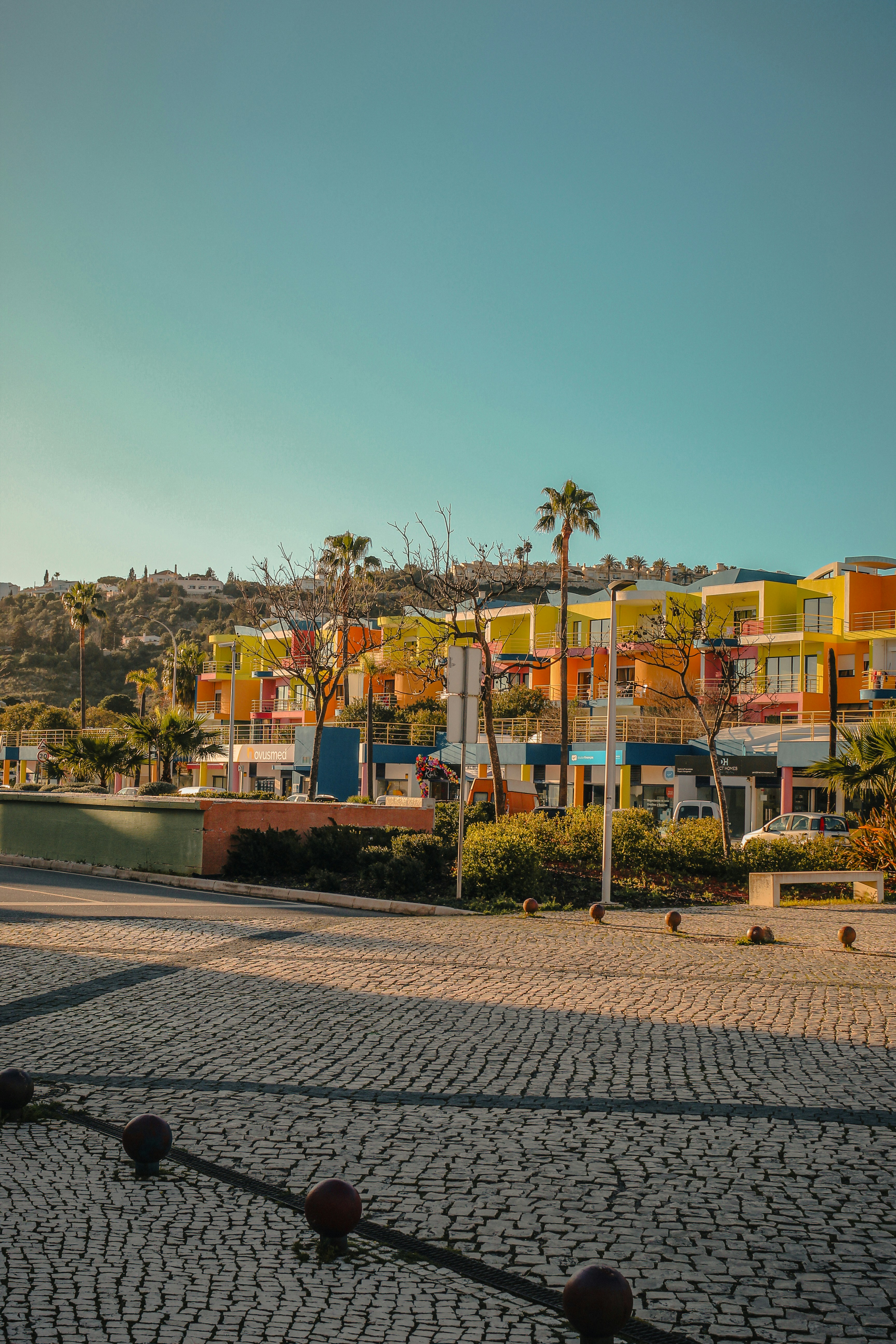 Casas modernas coloridas em uma encosta sob um céu limpo.