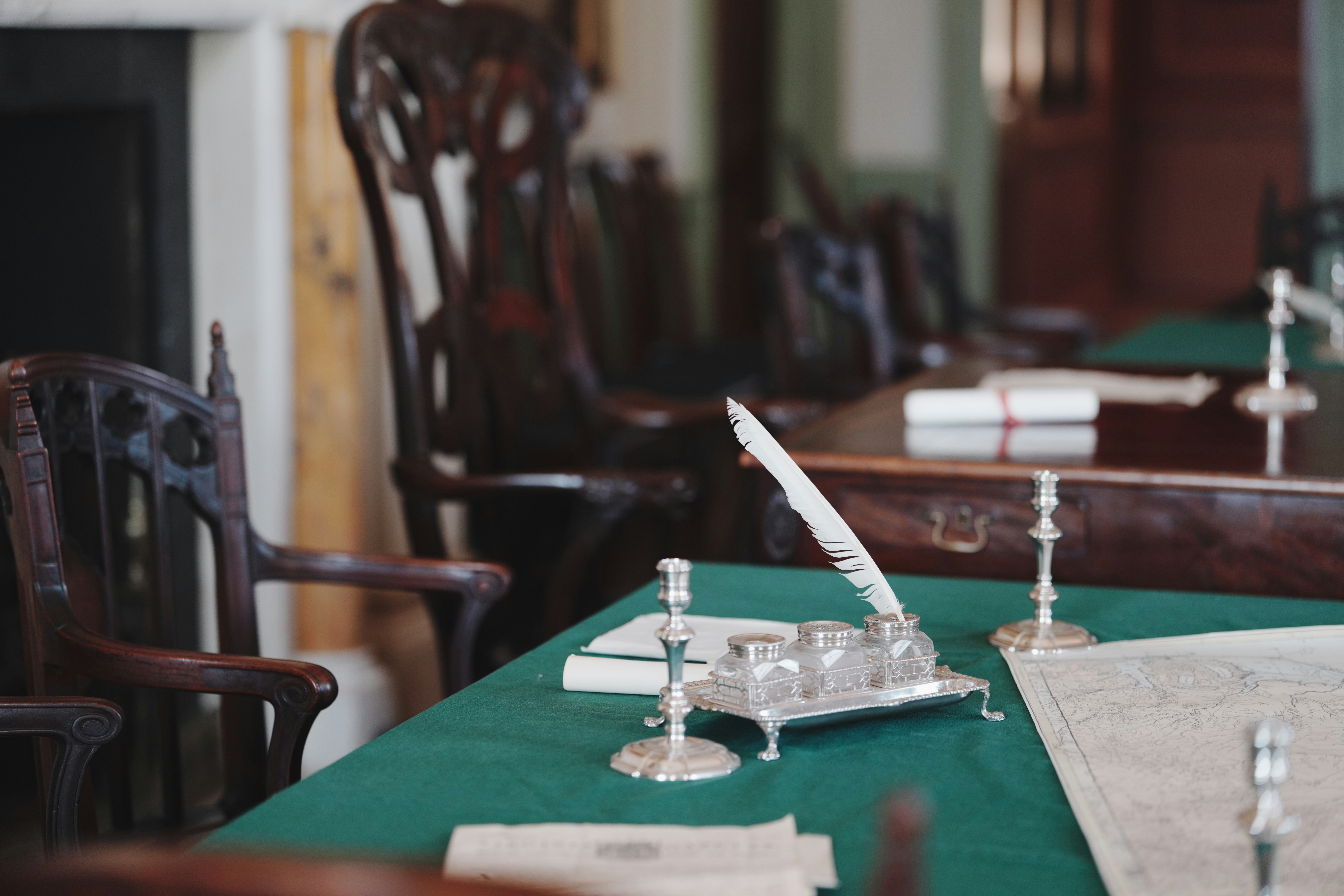 緑の机の上に置かれた羽ペンとインク壺