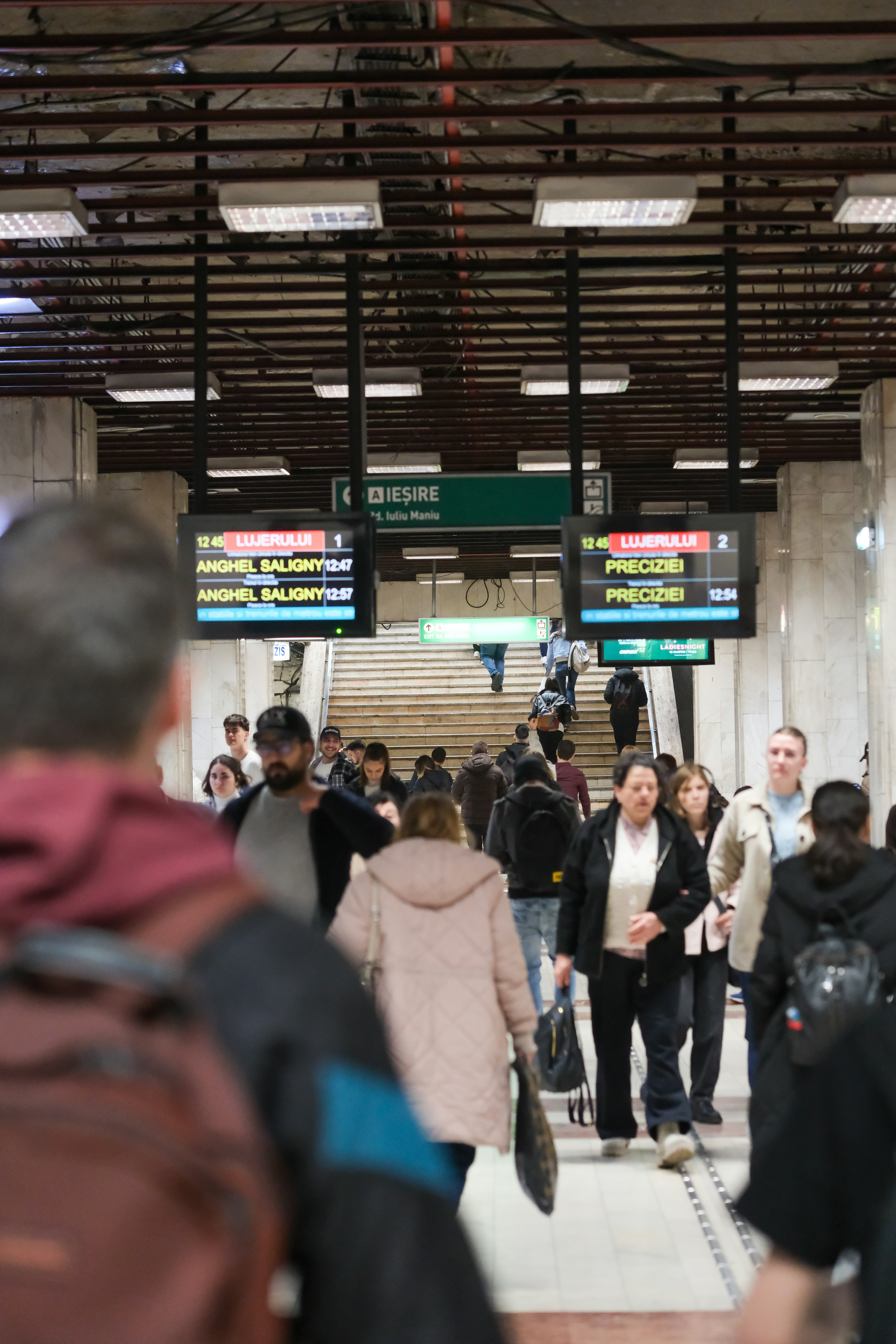 People walking up stairs in a busy subway station.