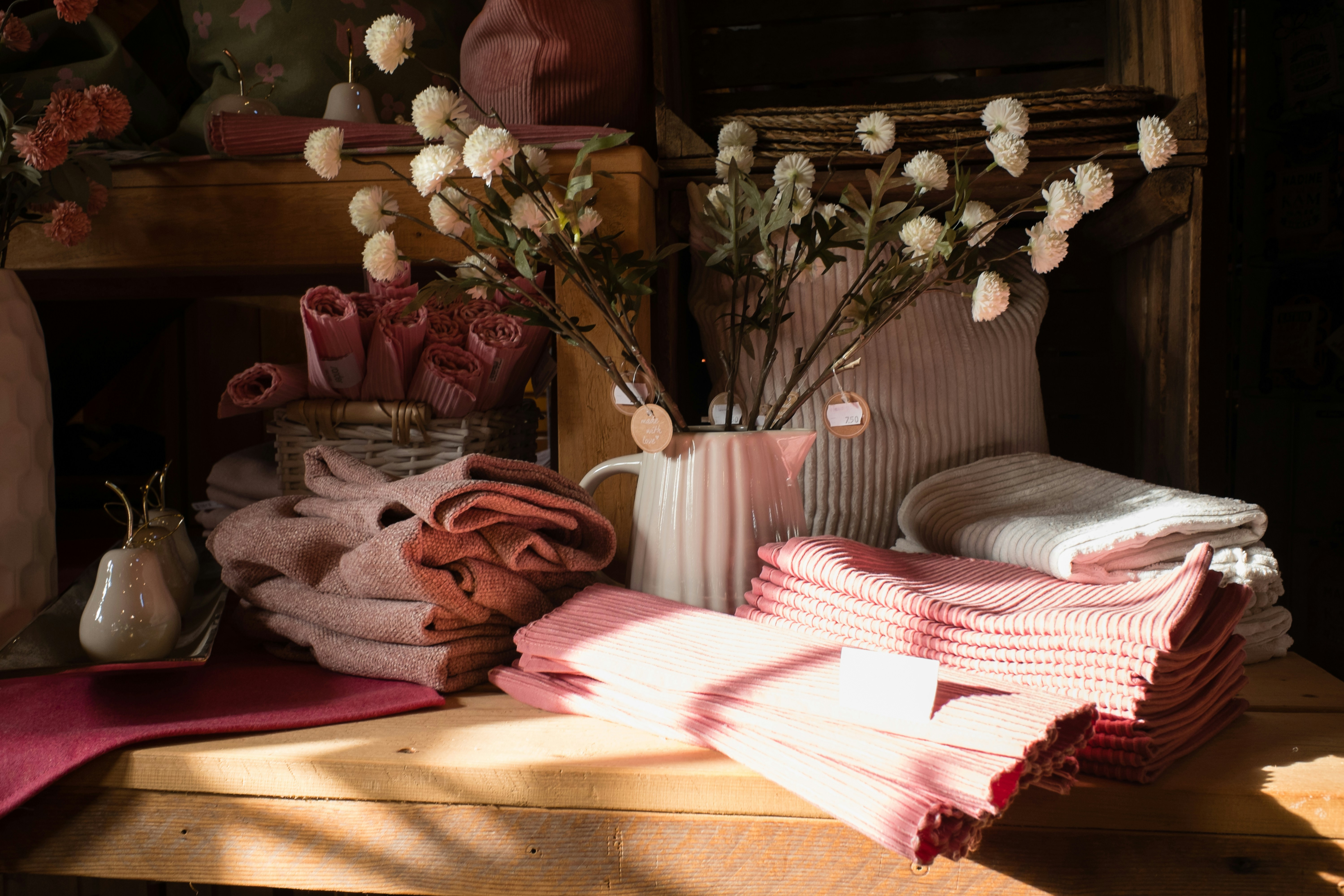 Pink and white textiles with flowers on a shelf.