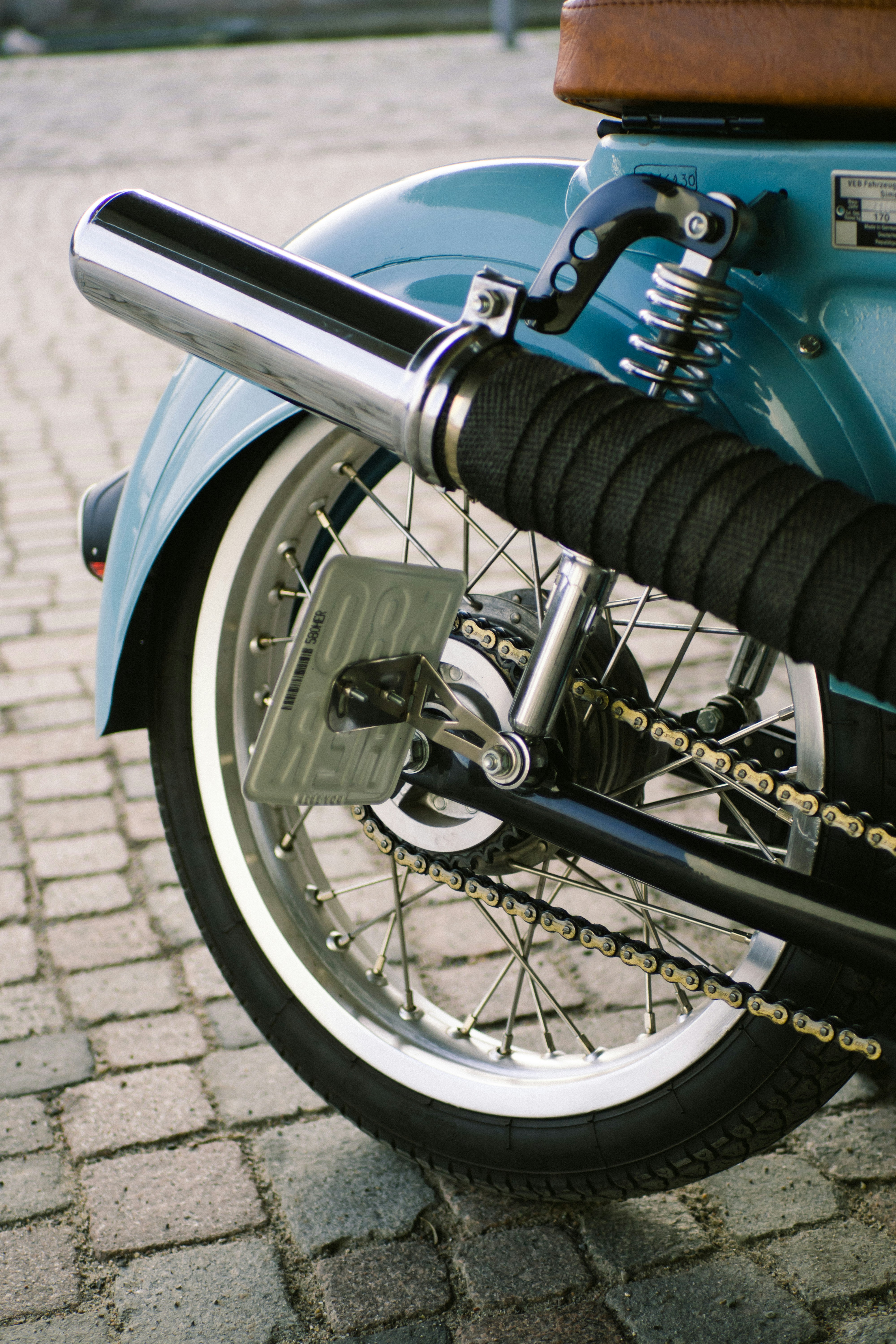 Close-up of a vintage motorcycle's exhaust and wheel.