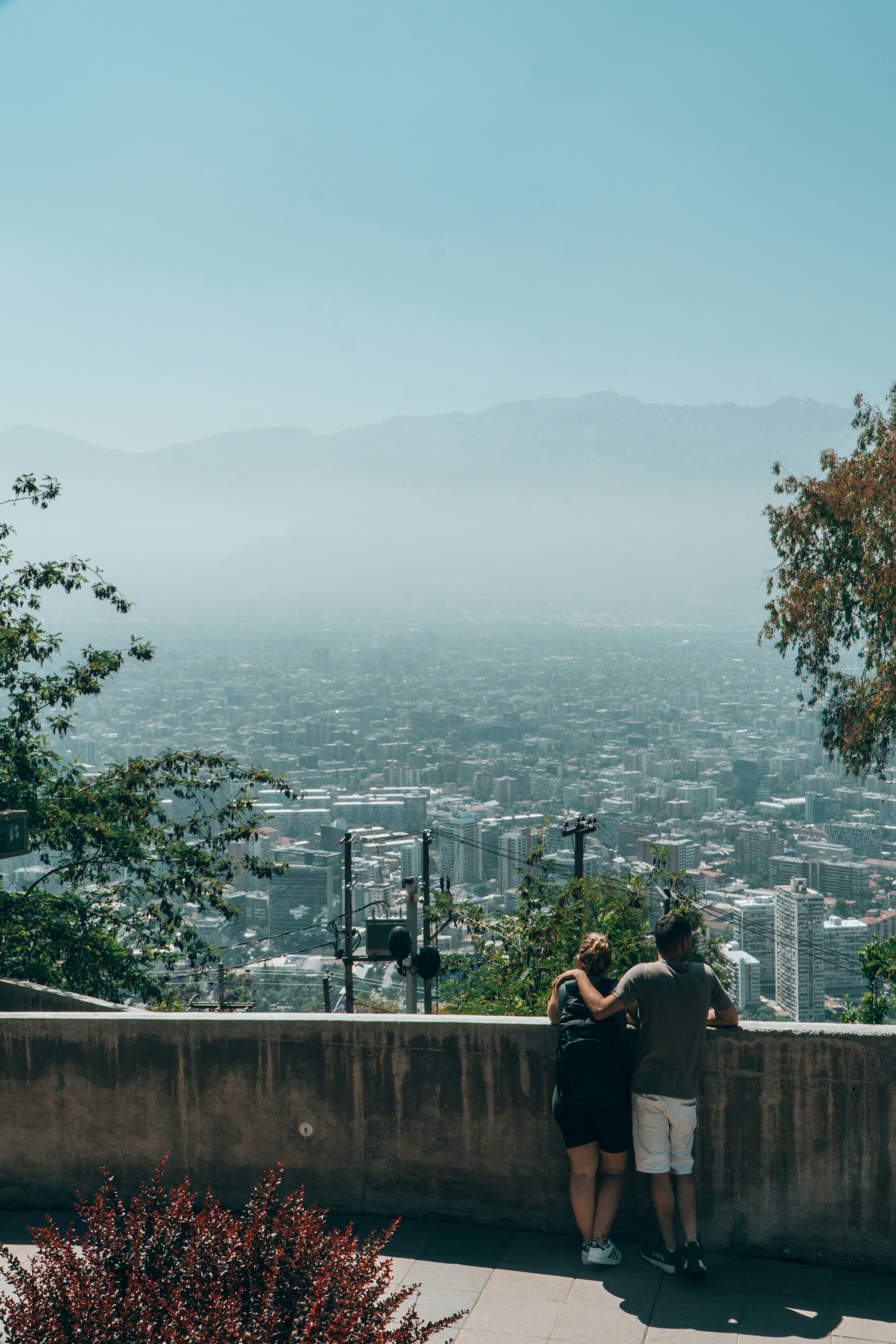 Couple looking out over a hazy cityscape from a viewpoint.