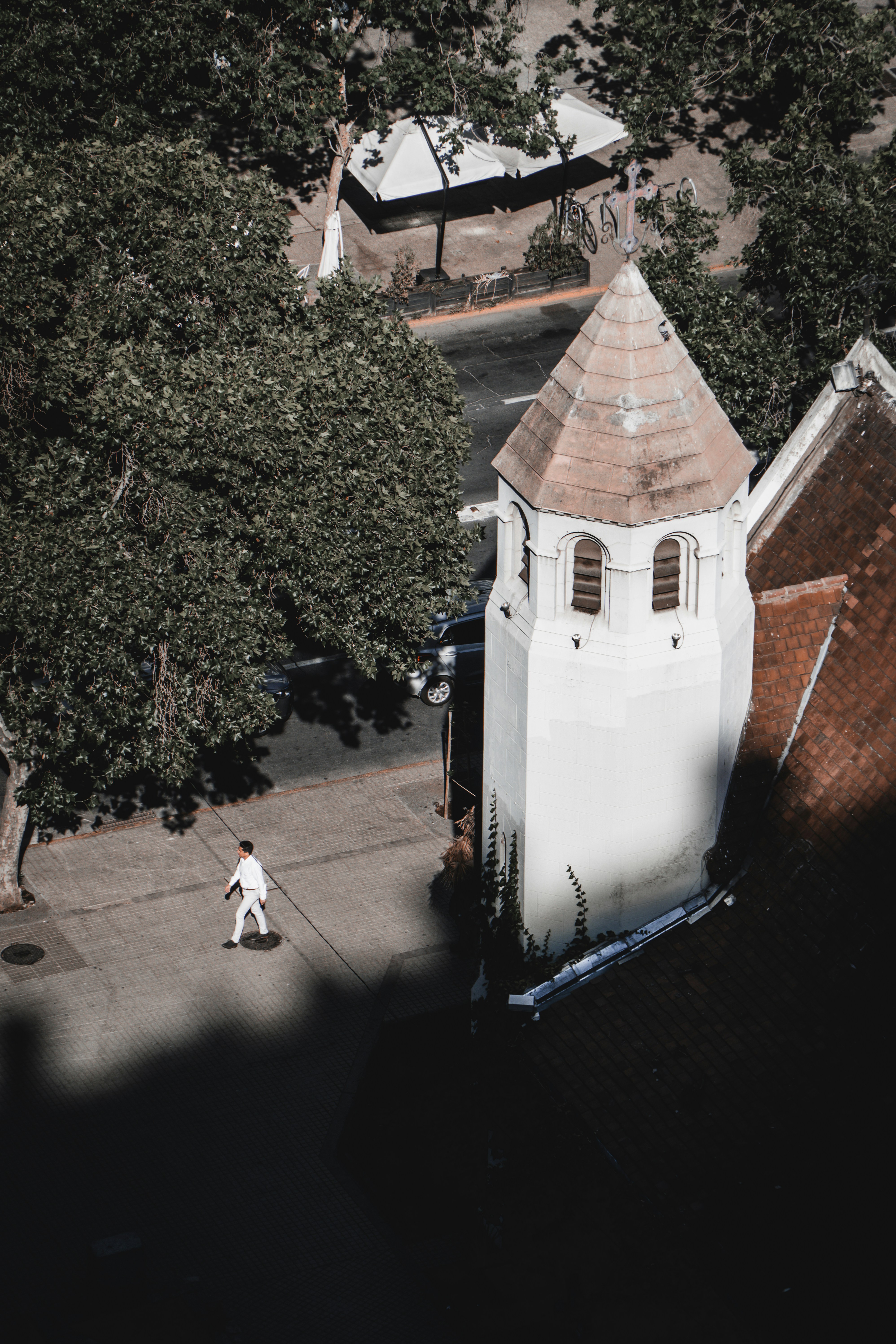 Man in white walks by church tower