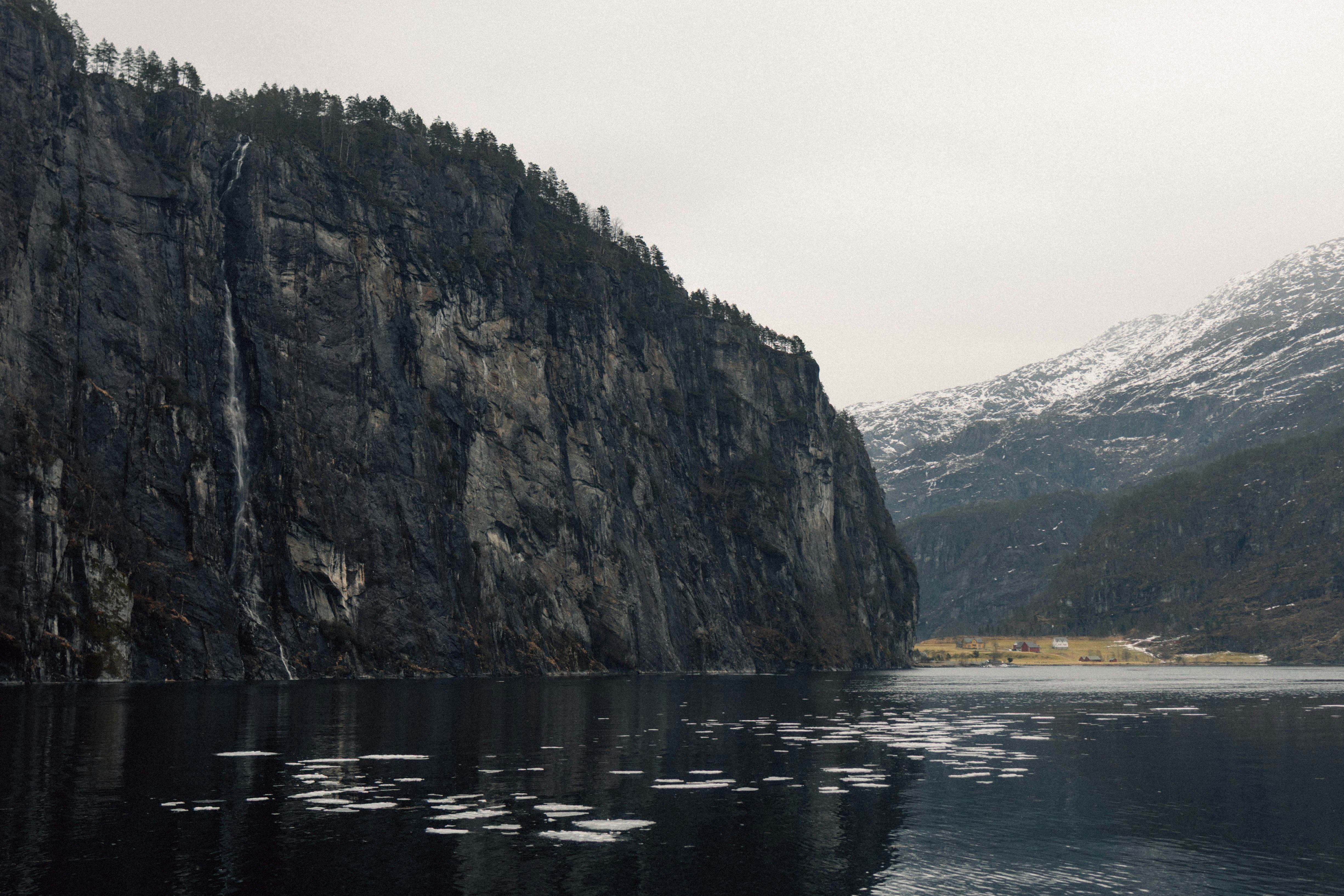 A steep cliff face overlooks a calm body of water.