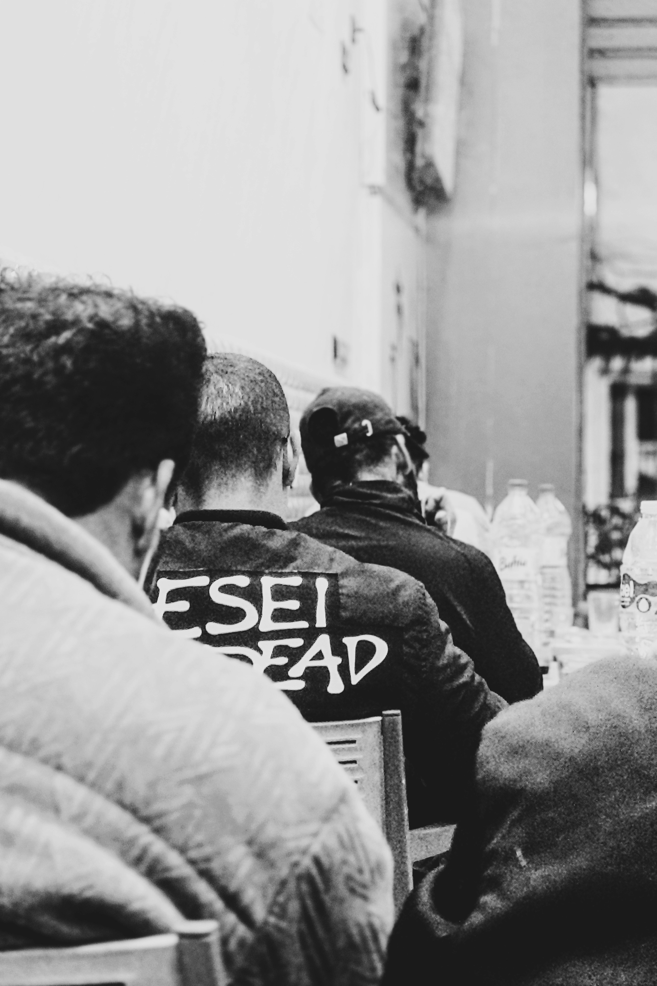 Gente sentada en mesas con texto en las chaquetas.