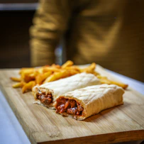Two wraps with french fries on a wooden board