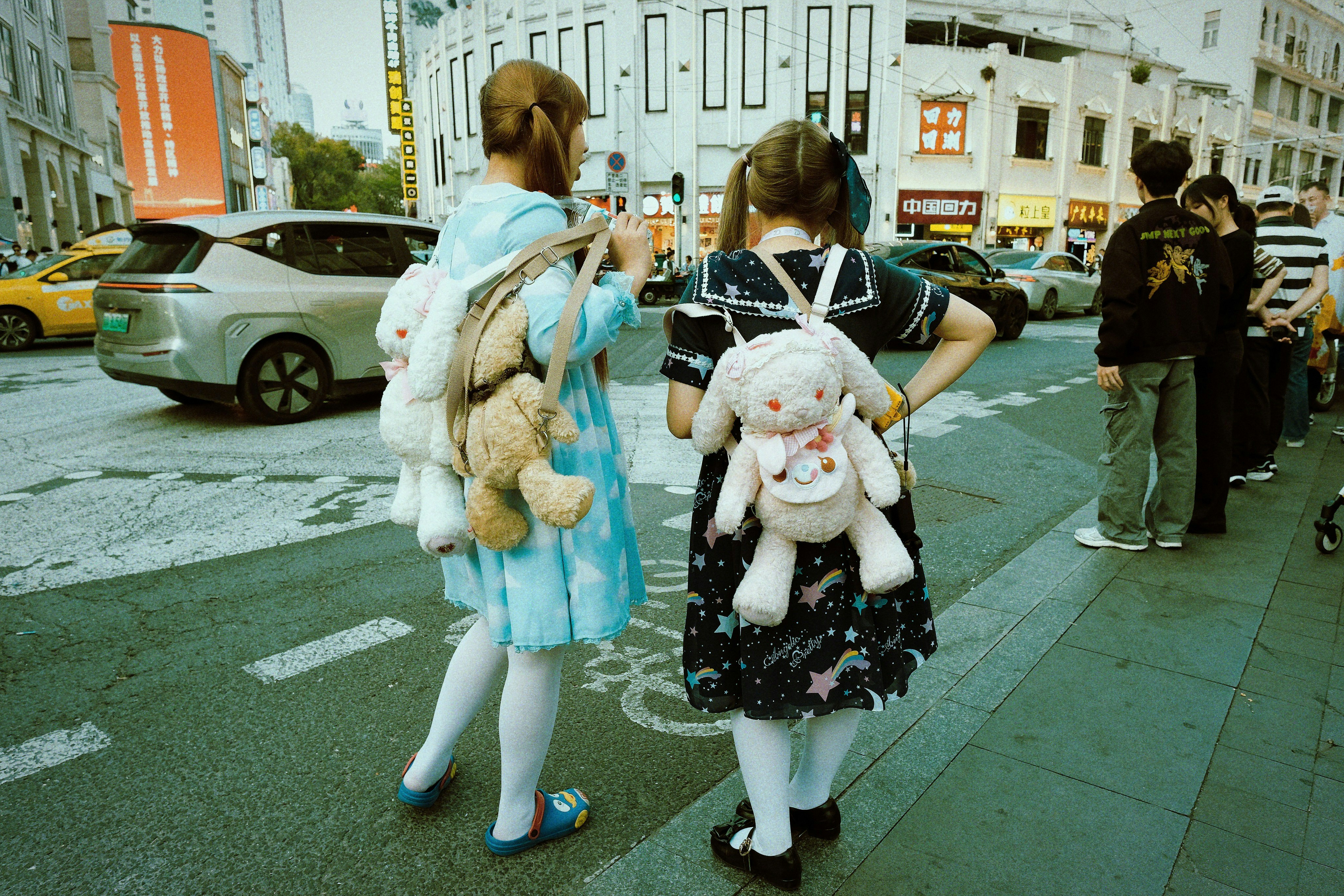 Two girls with stuffed animals on backpacks crosswalk
