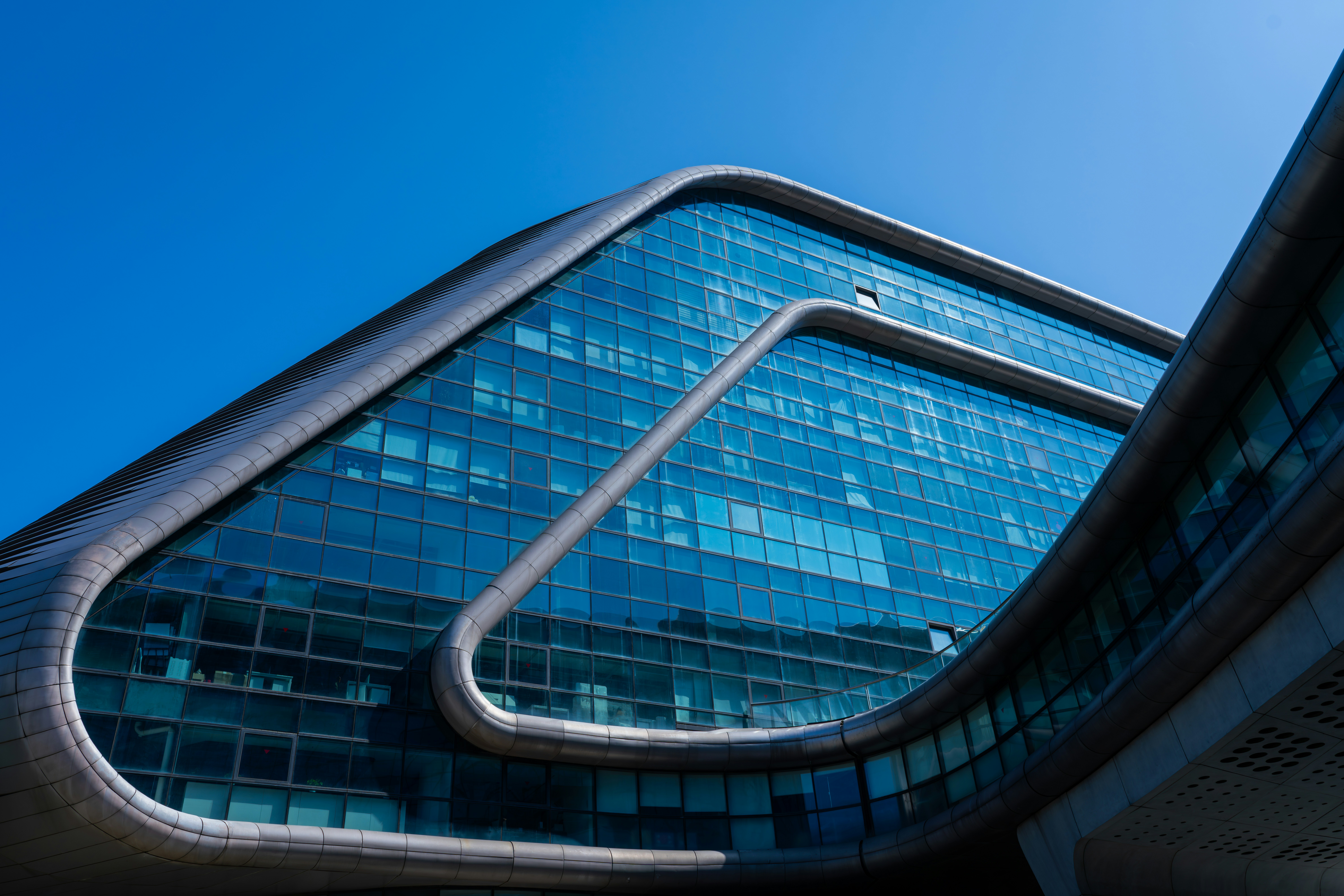 Modern glass building with curved architecture against blue sky