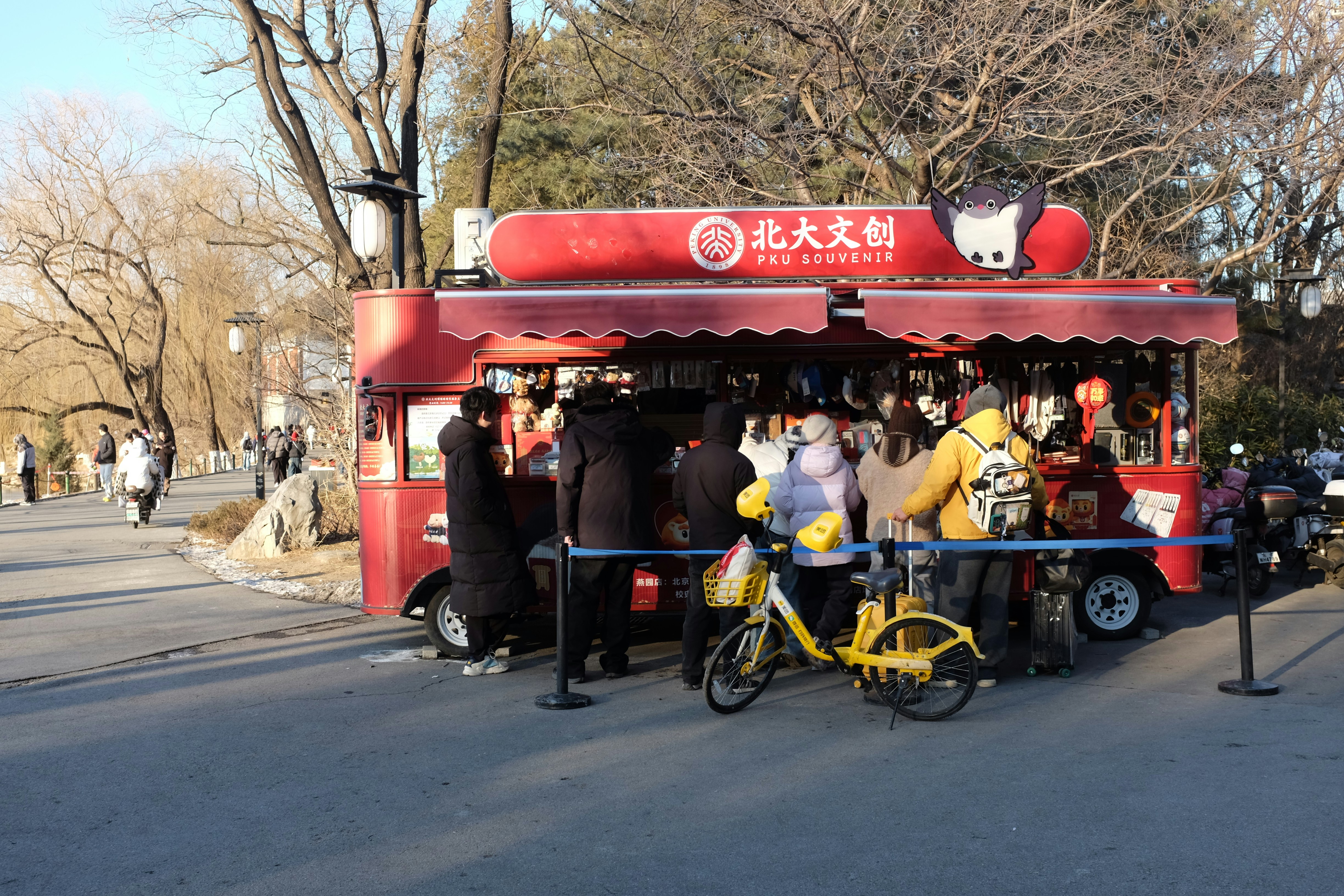 People queuing at a red food truck in a park