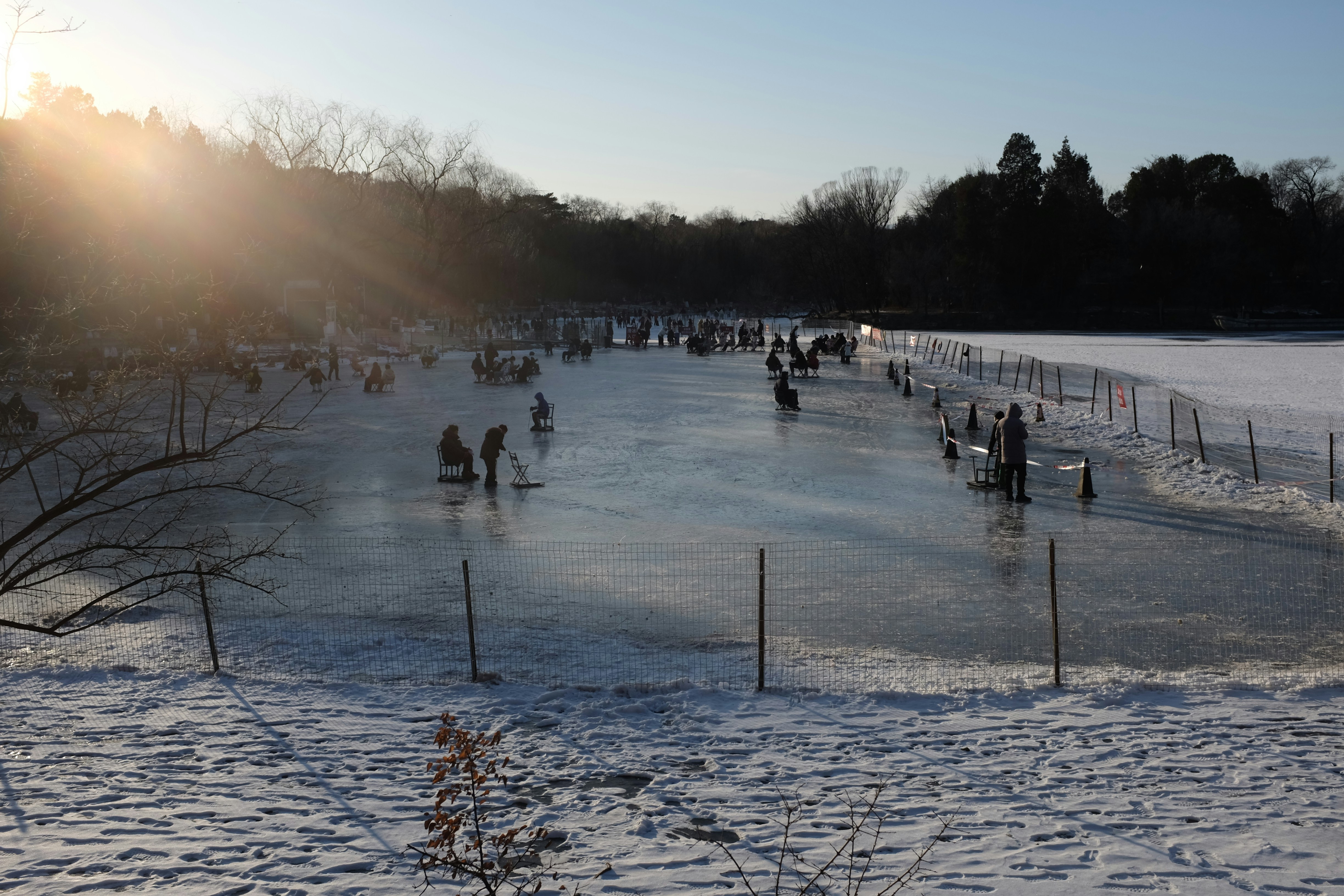 People ice skating on a frozen lake at sunset