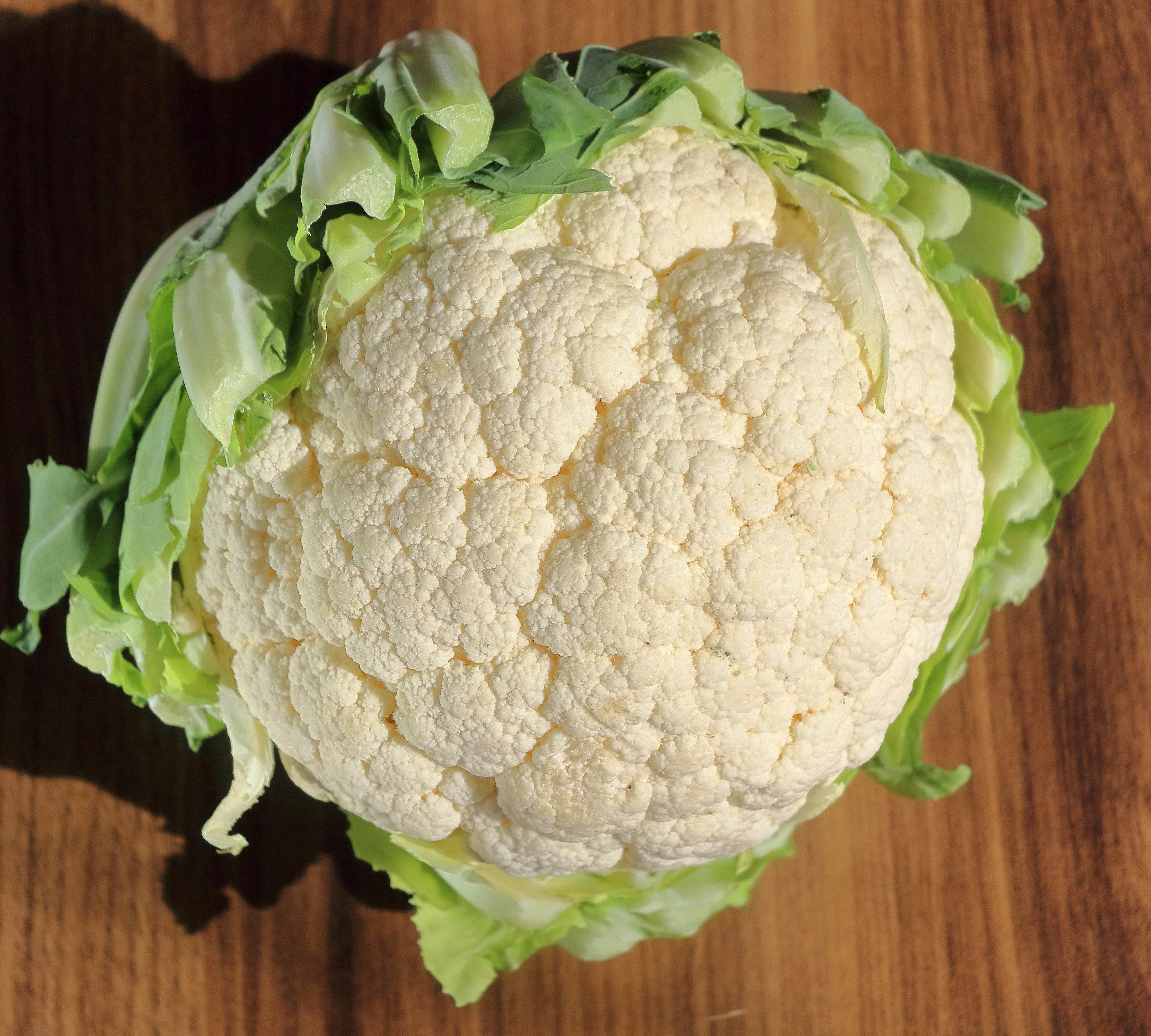A fresh head of cauliflower on a wooden surface