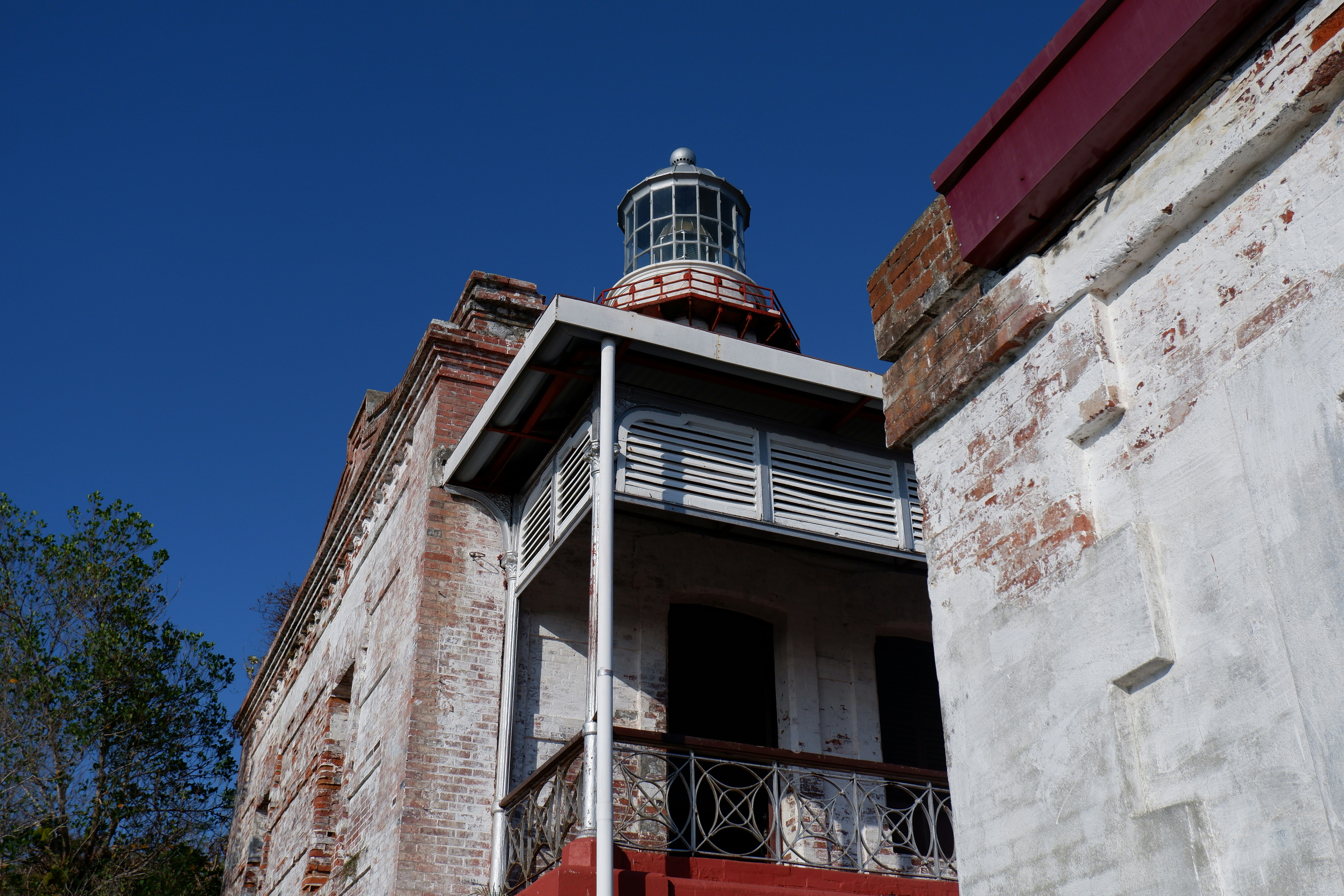 Farol antigo com paredes de tijolos desgastadas e uma varanda.