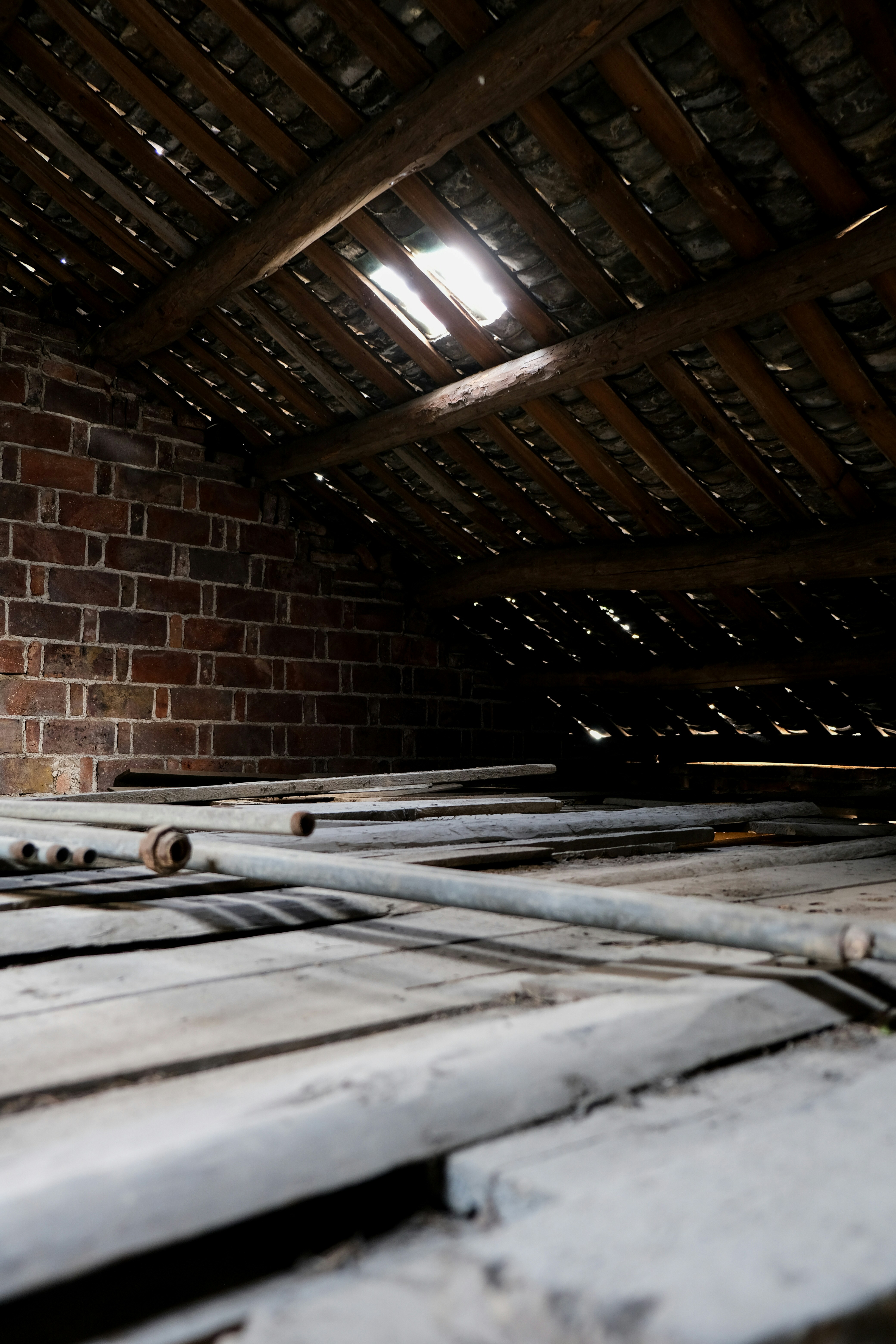 Holzdielen auf einem staubigen Dachboden mit Backsteinwand.