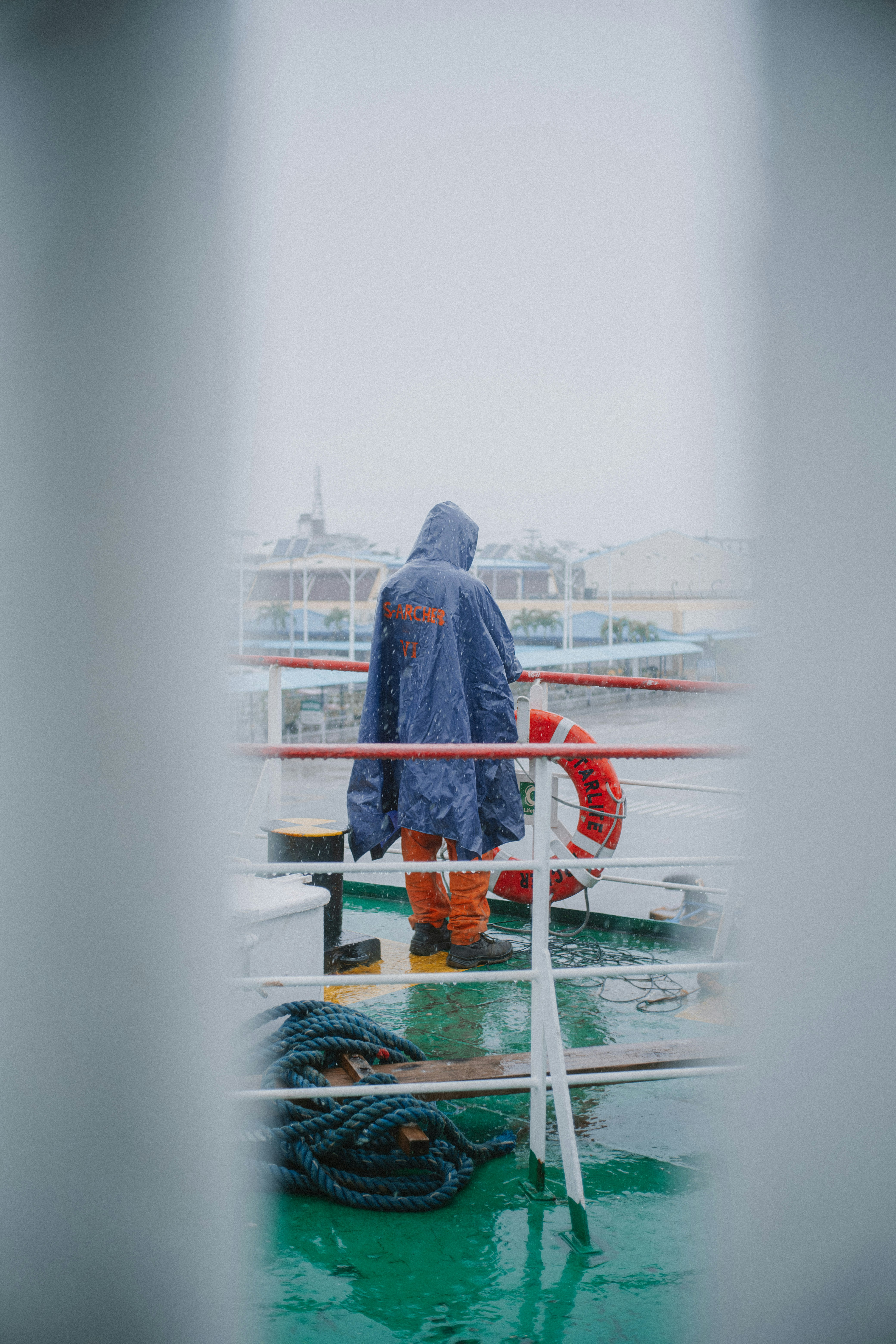 Persona con impermeable en la cubierta de un barco mojado
