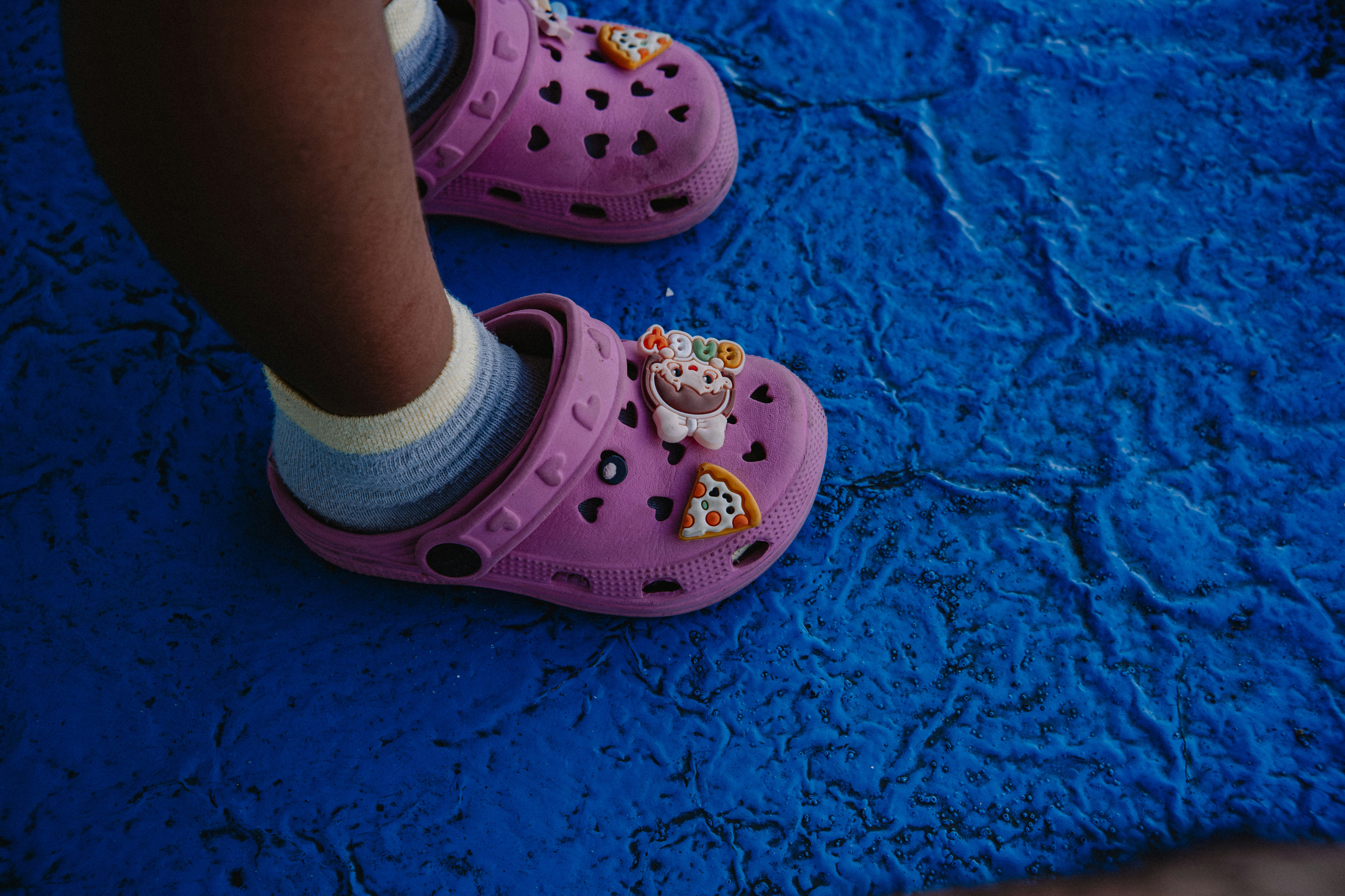 Zuecos rosas de niño con amuletos sobre una estera azul