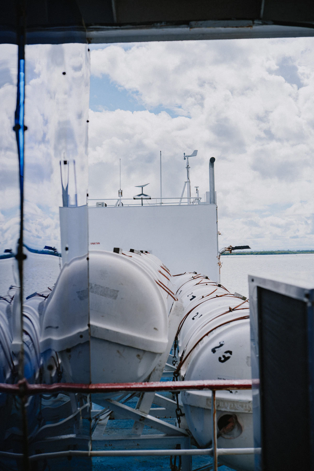 Lifeboats on an unrelated ferry deck under cloudy skies