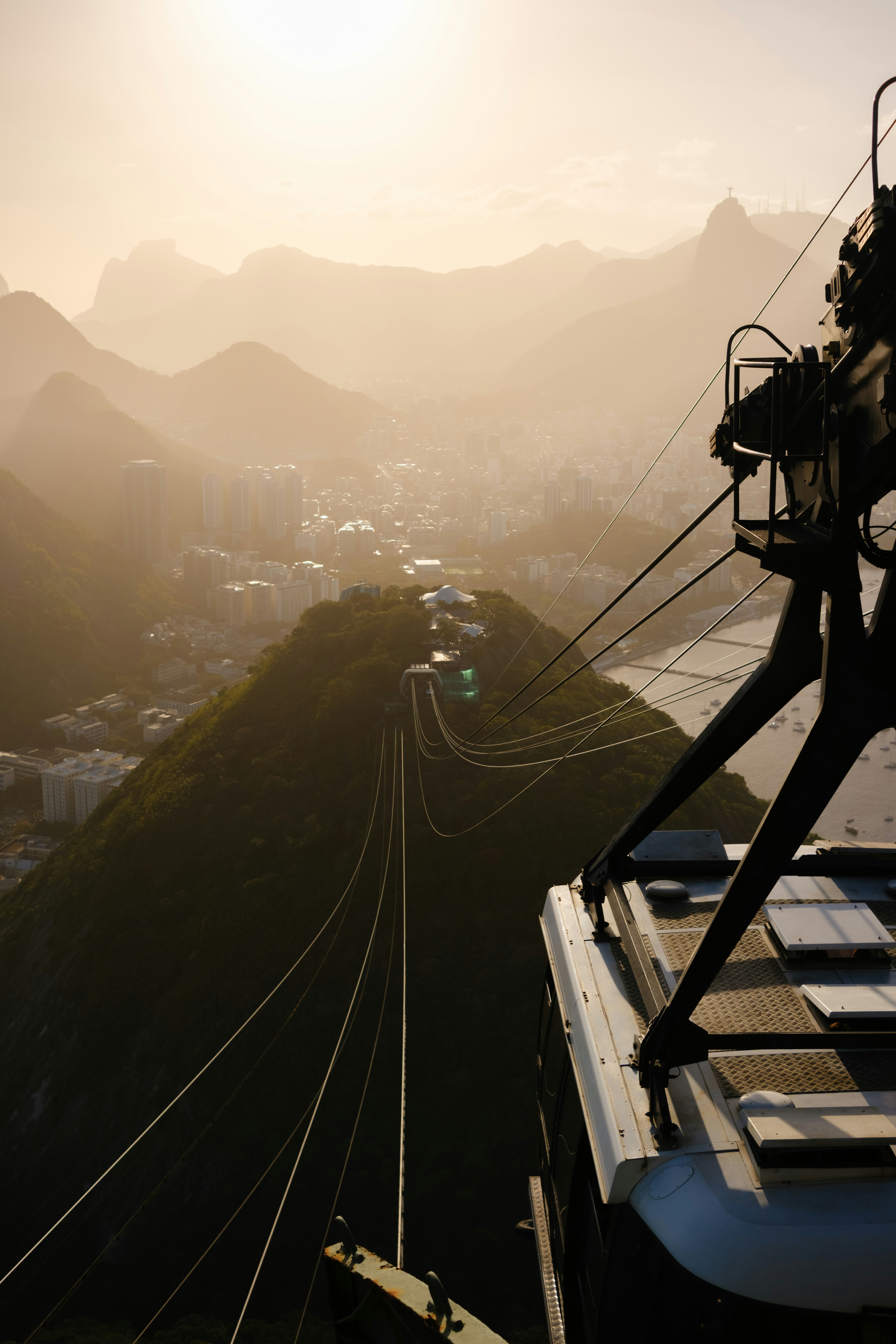 Cable car ascending towards a hazy mountain landscape at sunset.