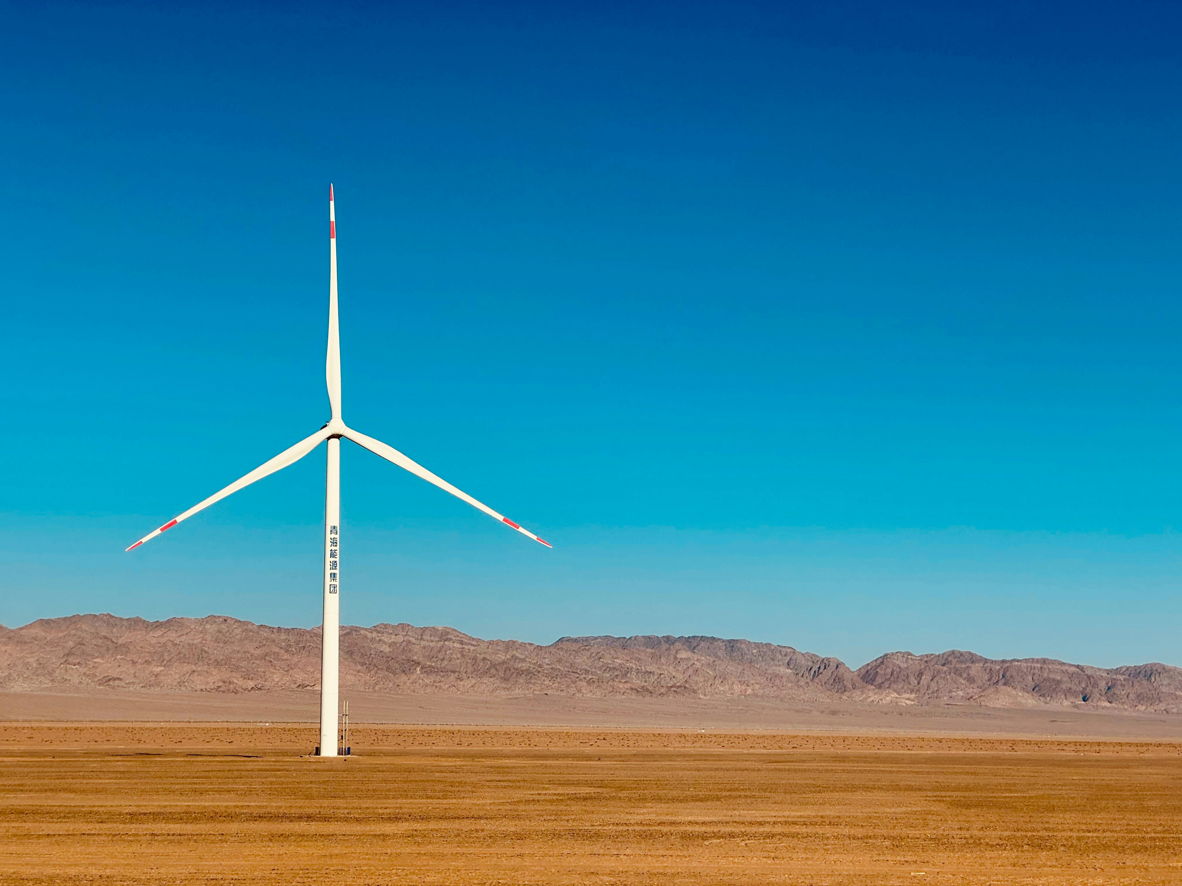Uma turbina eólica solitária está em uma vasta paisagem árida.