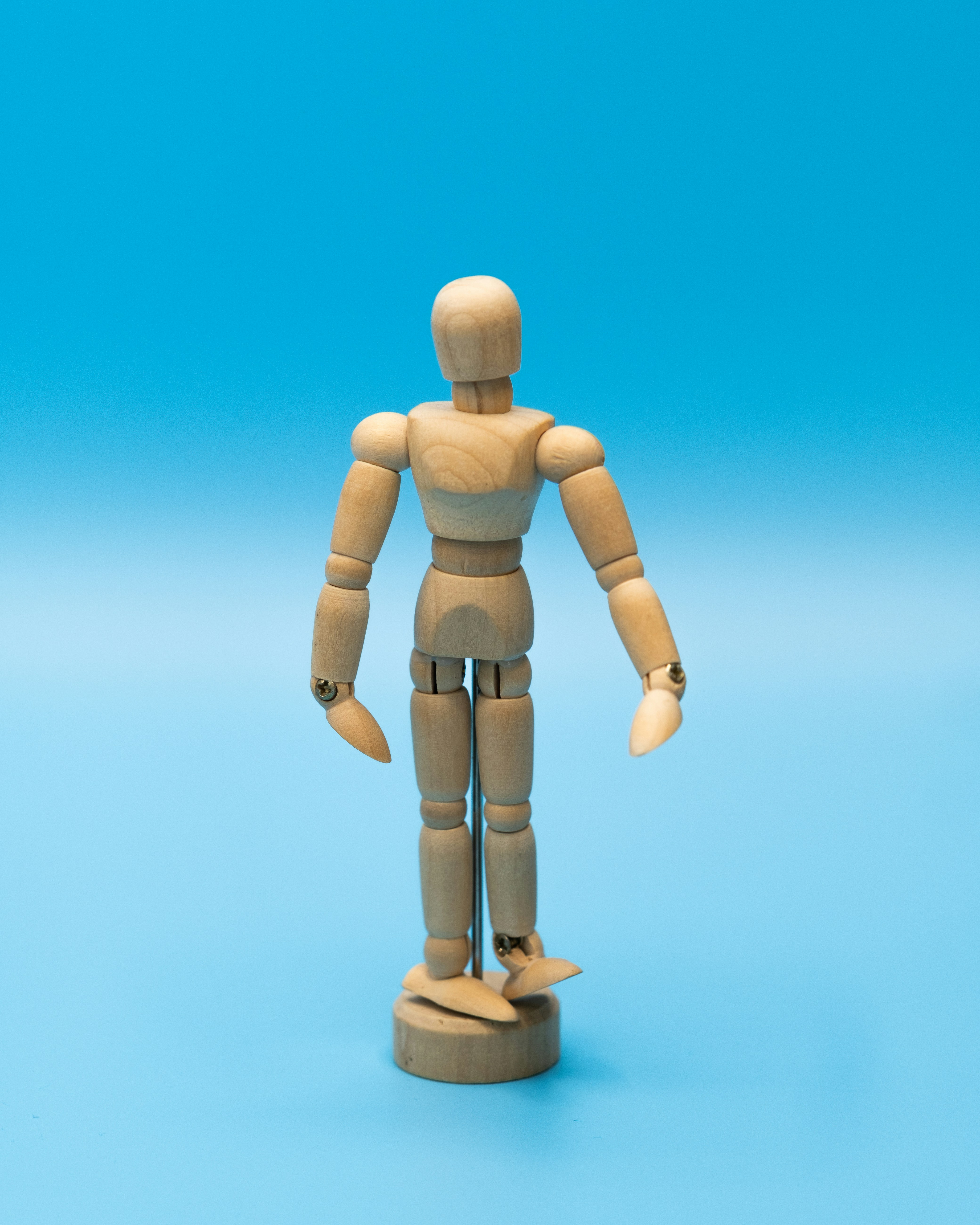 Wooden mannequin standing on a blue background