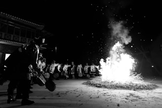People gather around a large bonfire at night