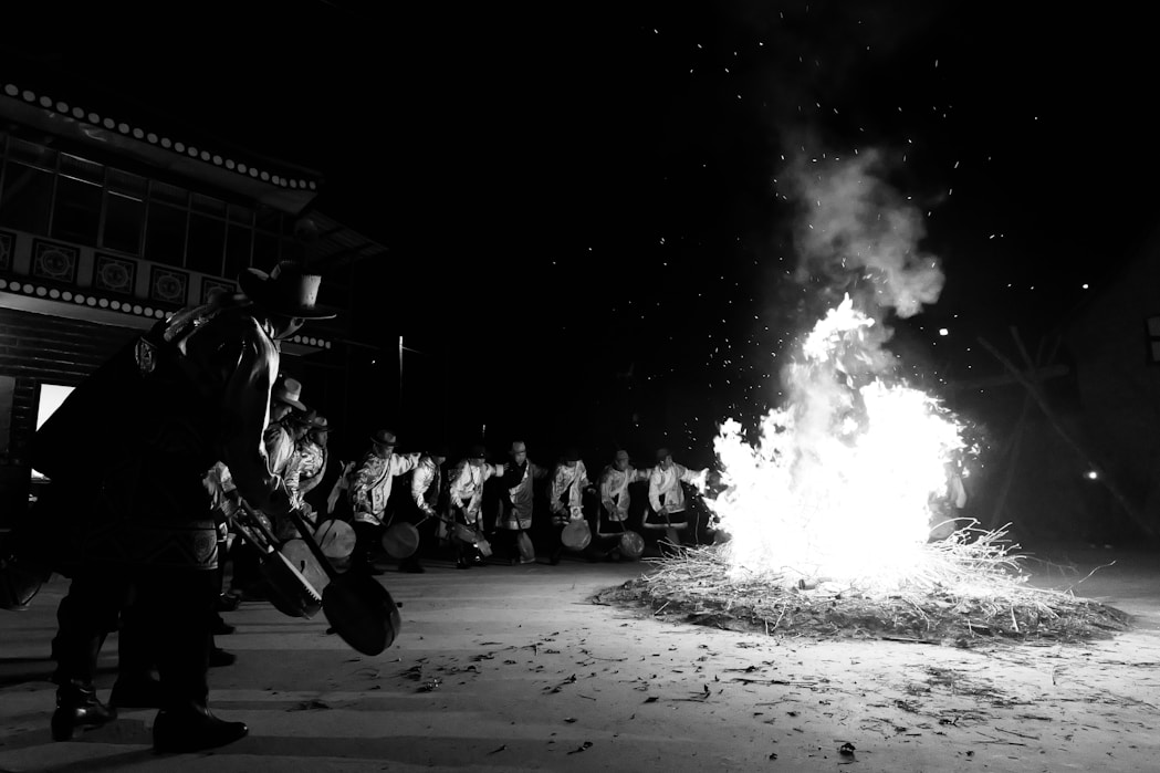 People gather around a large bonfire at night