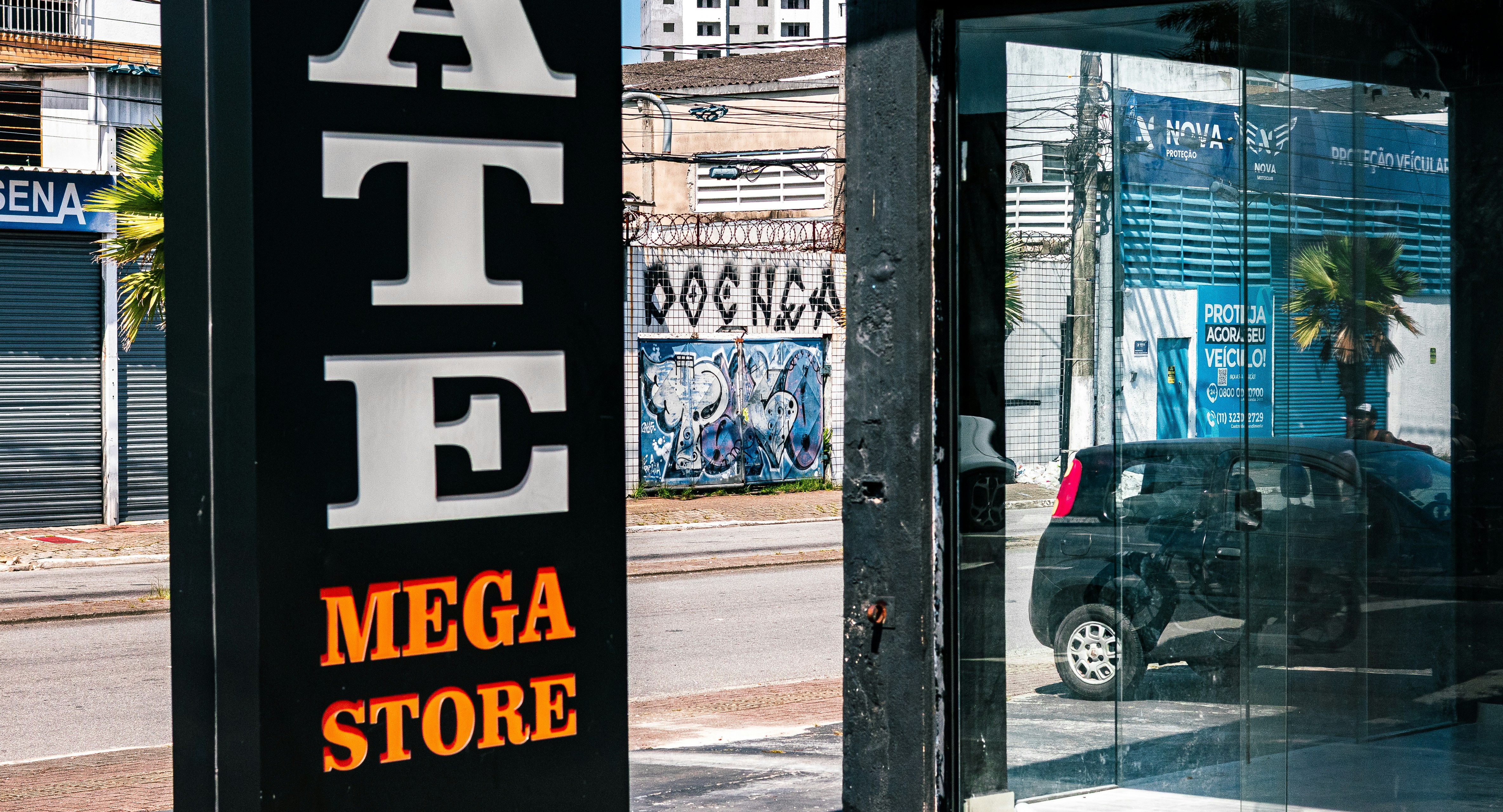Urban storefront with graffiti and a parked car, reflecting a sense of commercial activity and urban decay.