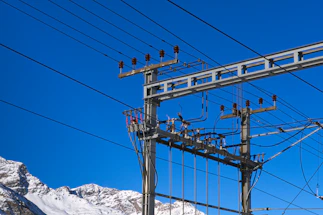 Power lines against a clear blue sky with mountains.
