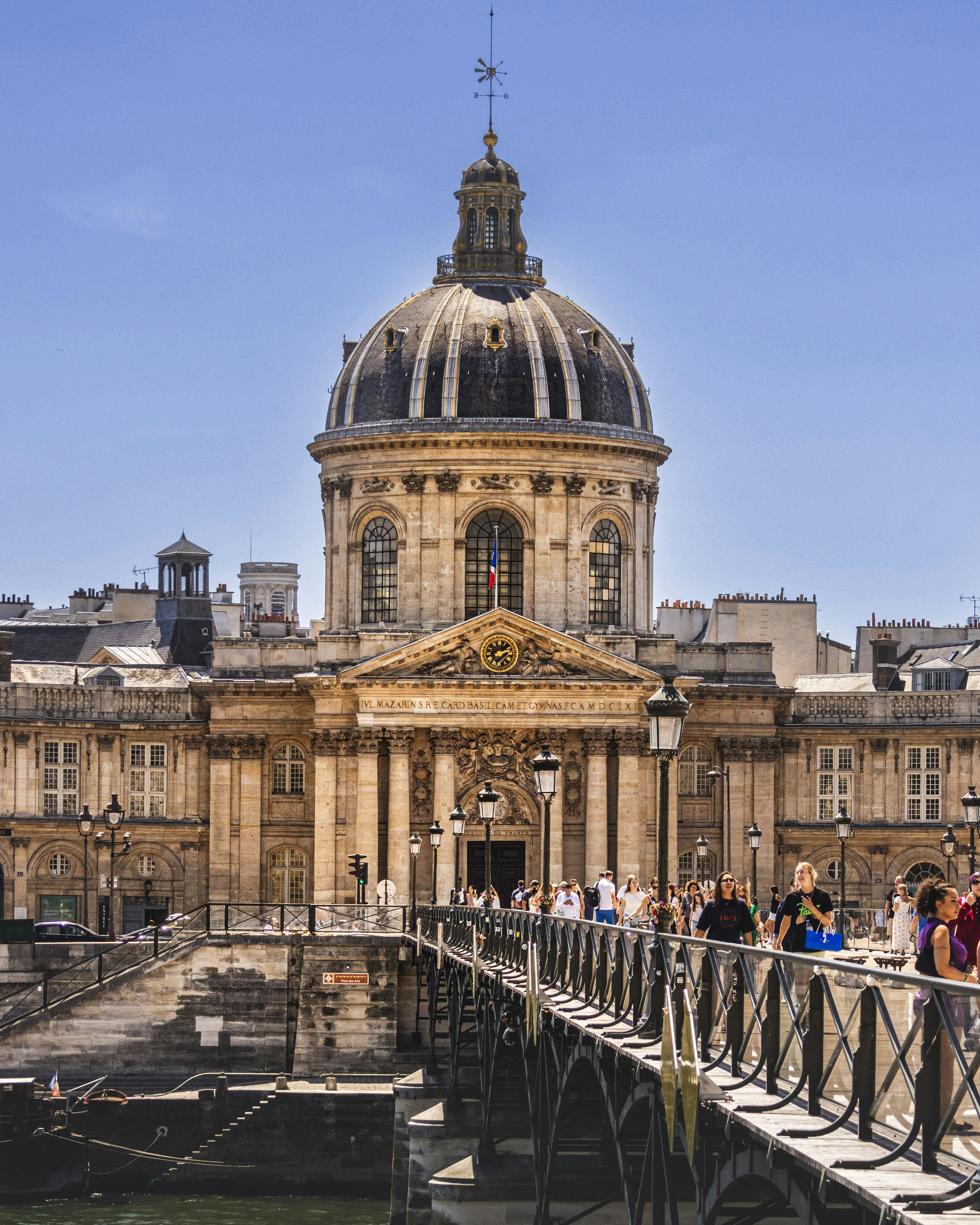 Gente cruzando un puente hacia un gran edificio abovedado