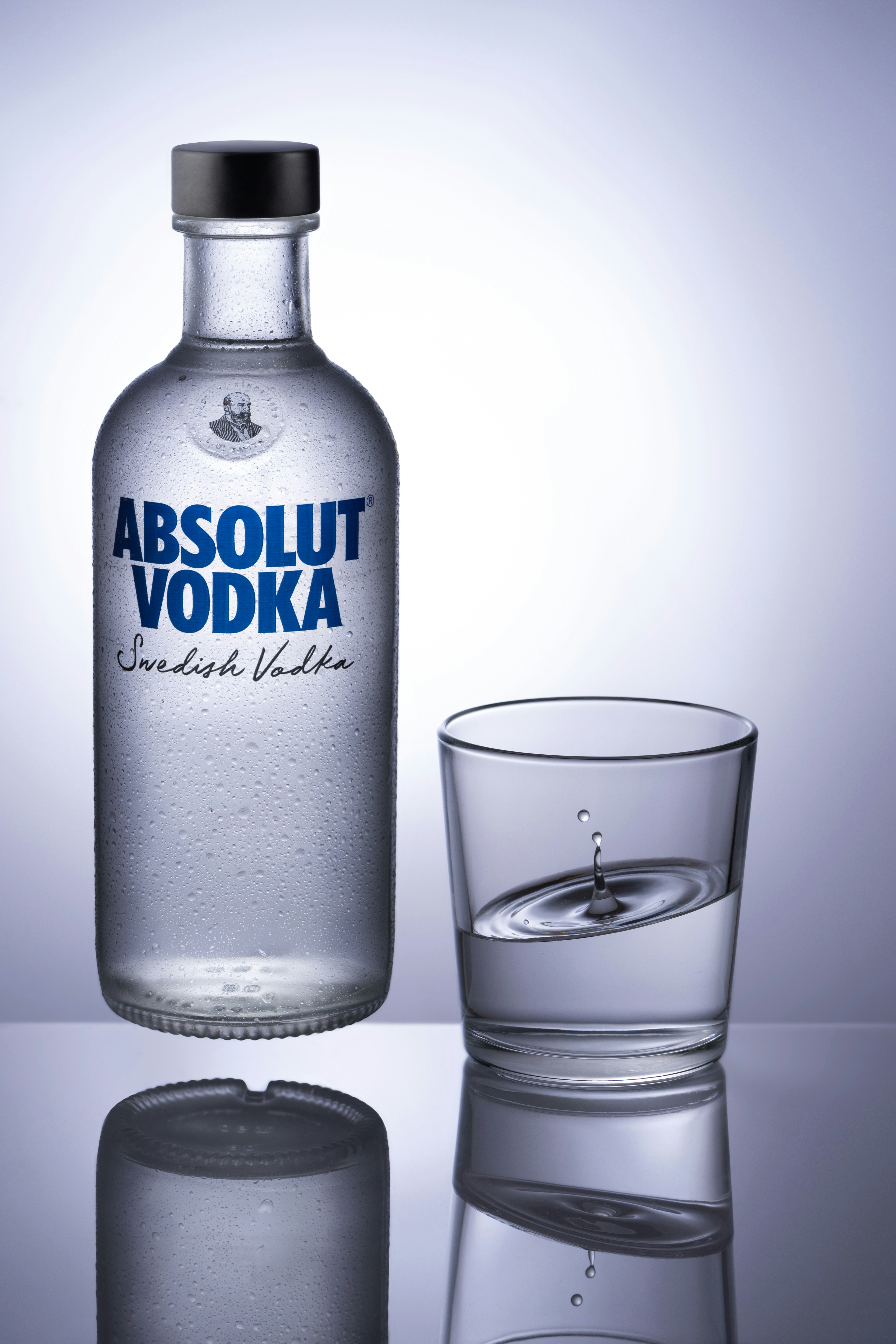Bottiglia di vodka Absolut con un bicchiere di liquido trasparente.