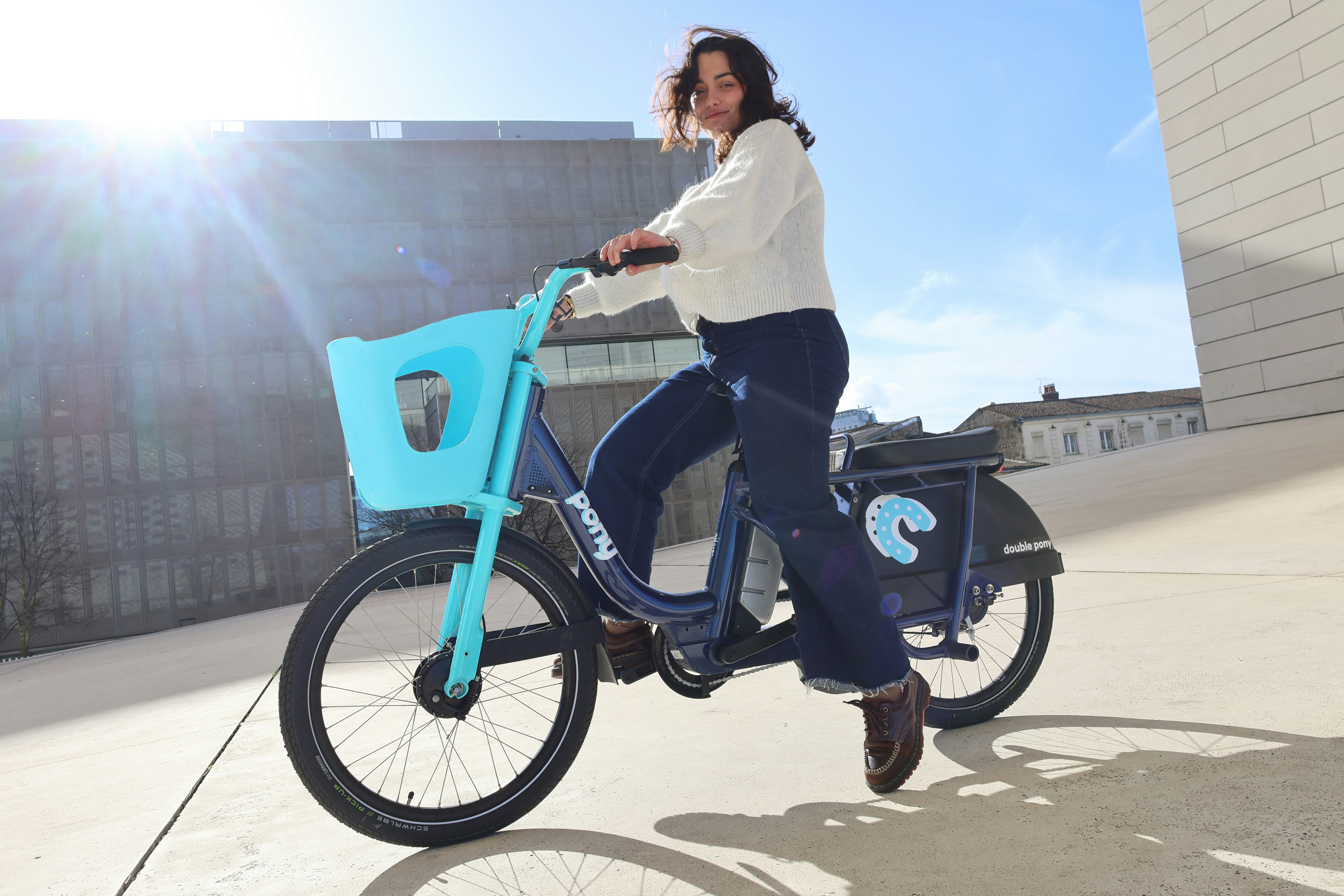 Eine Frau fährt ein blaues Fahrrad mit einem Korb.
