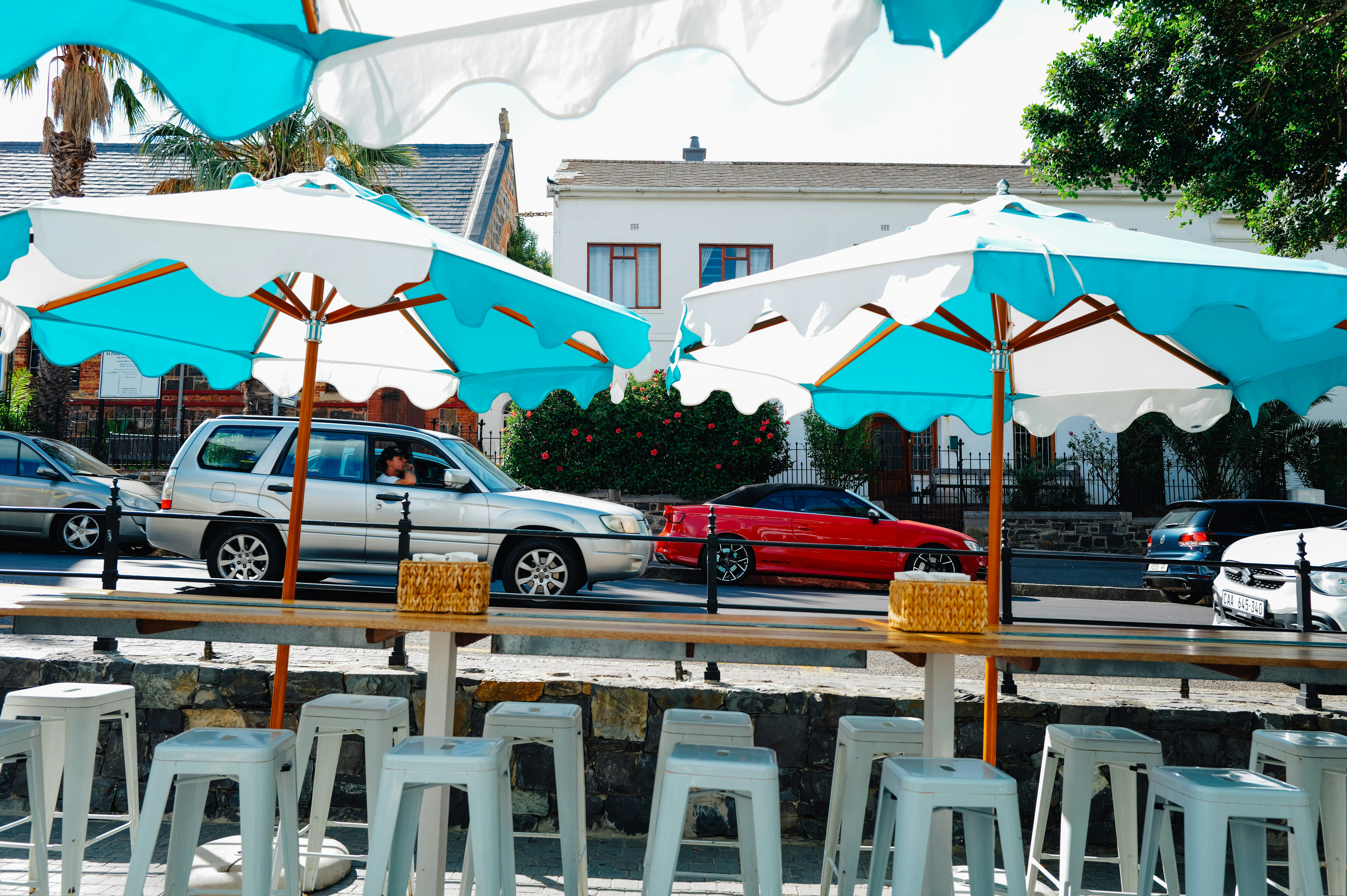 Outdoor seating with umbrellas and cars passing by