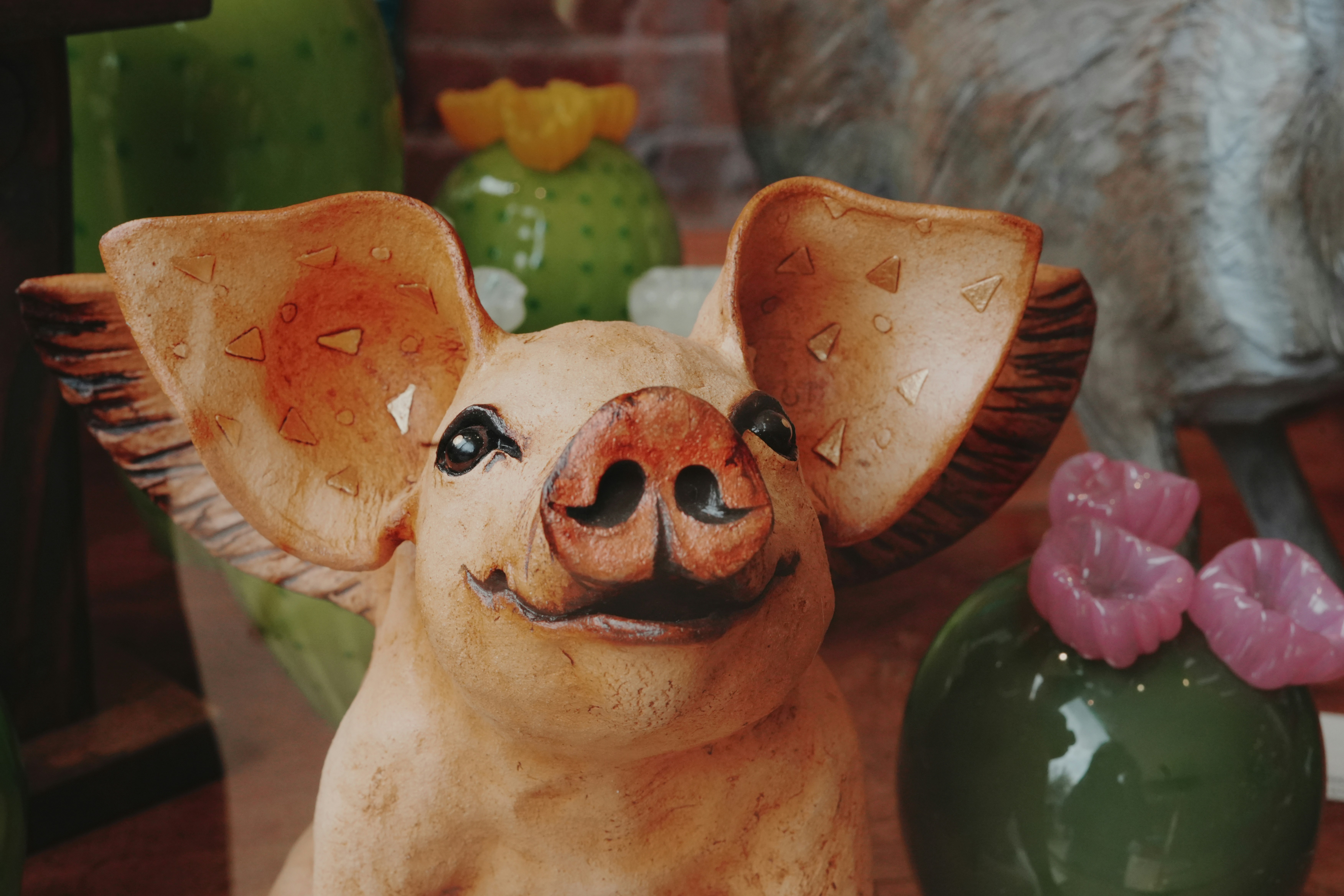 Um porco de cerâmica com grandes orelhas e decorações de cacto.