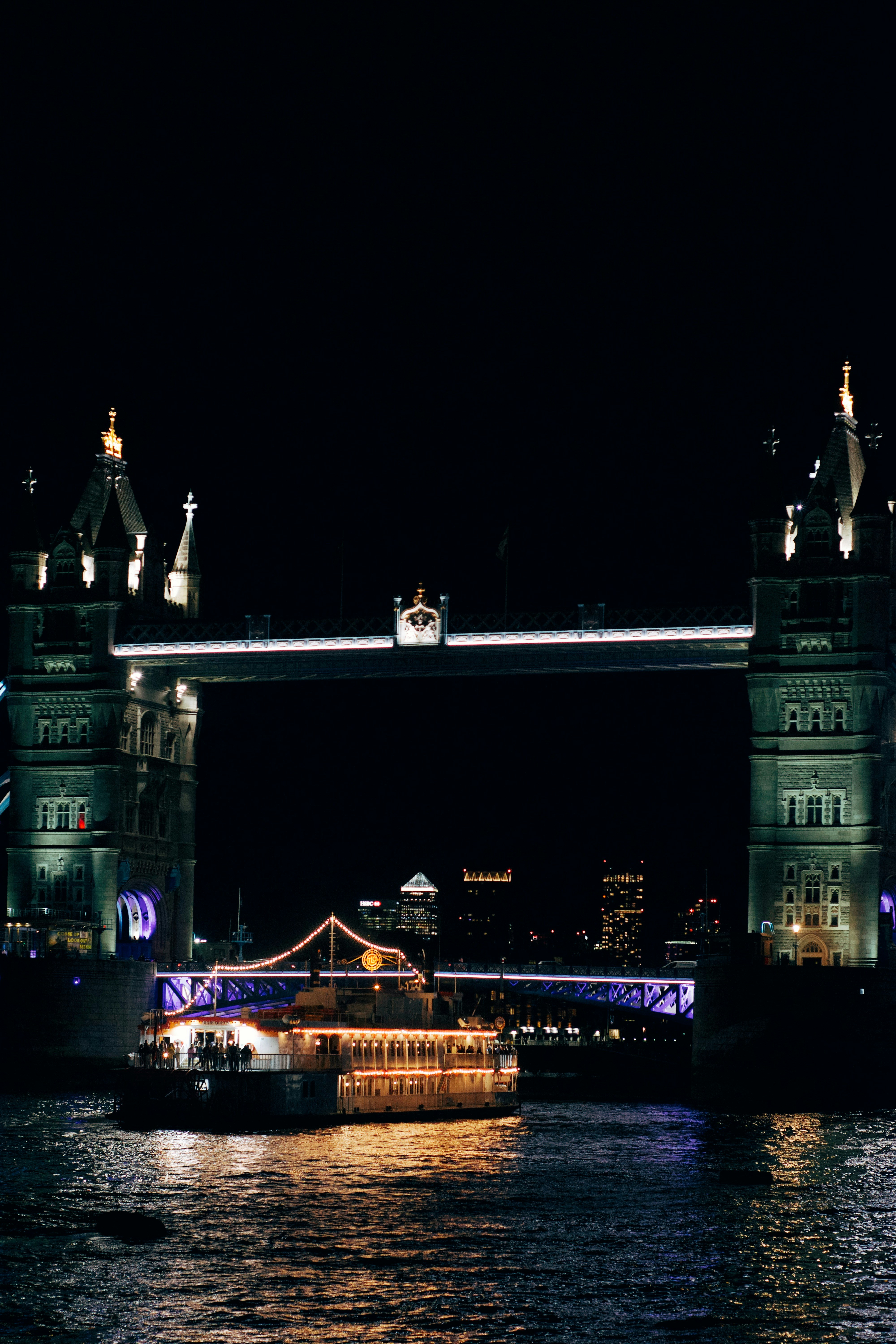 Puente de la torre iluminado por la noche con barco en el río