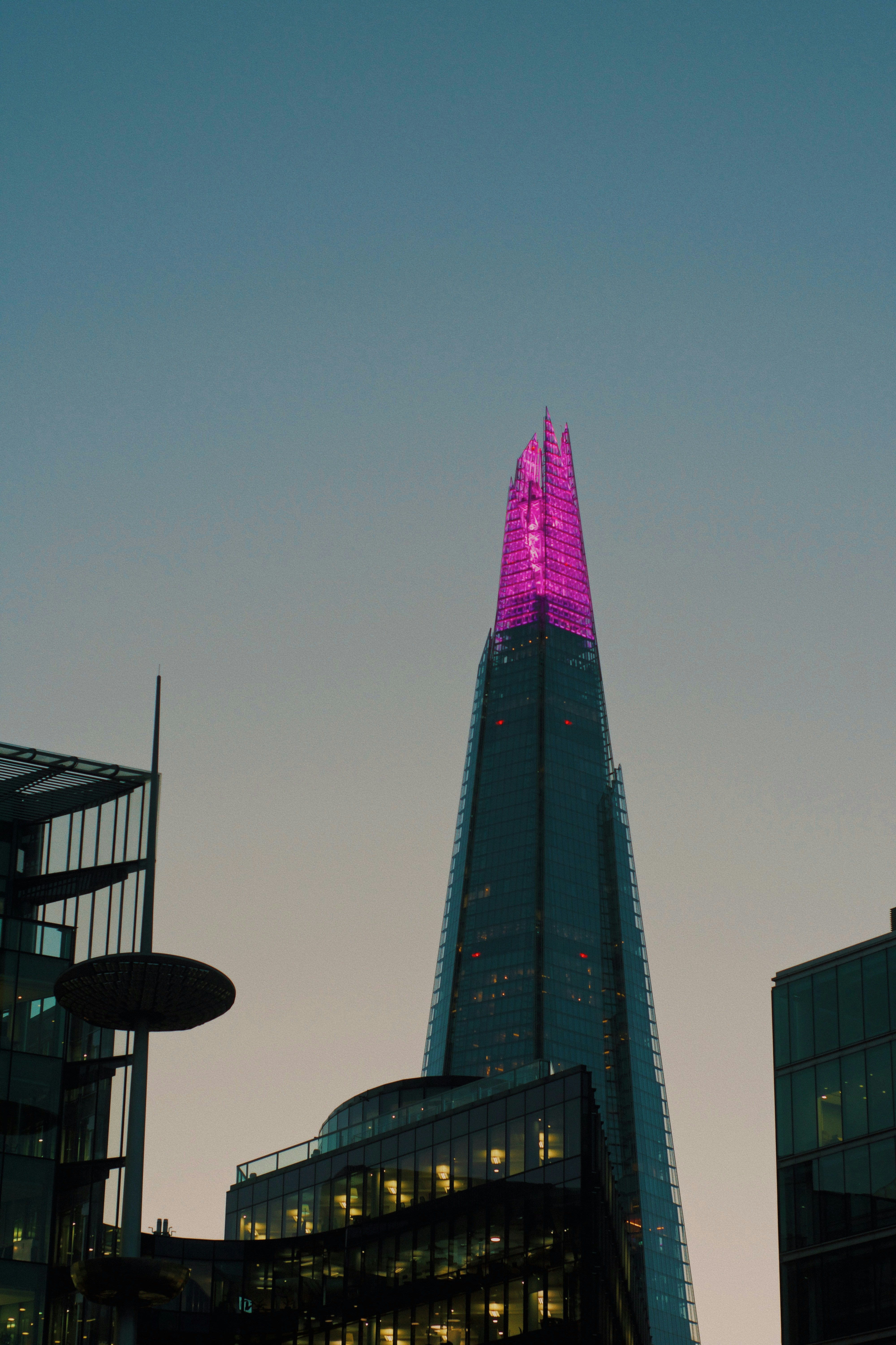 Rascacielos moderno con techo iluminado en rosa al anochecer
