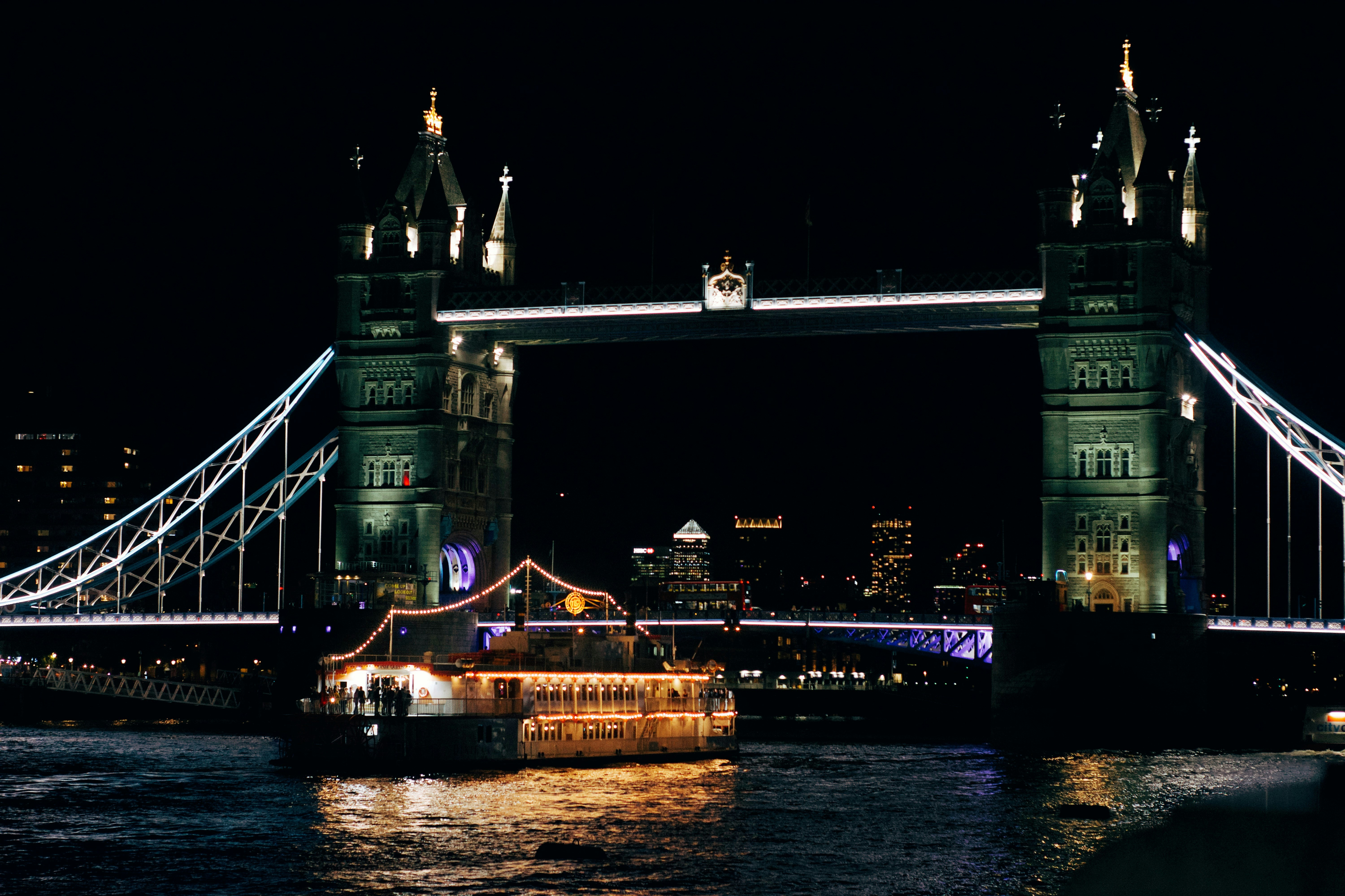 Puente torre iluminado por la noche con un barco.