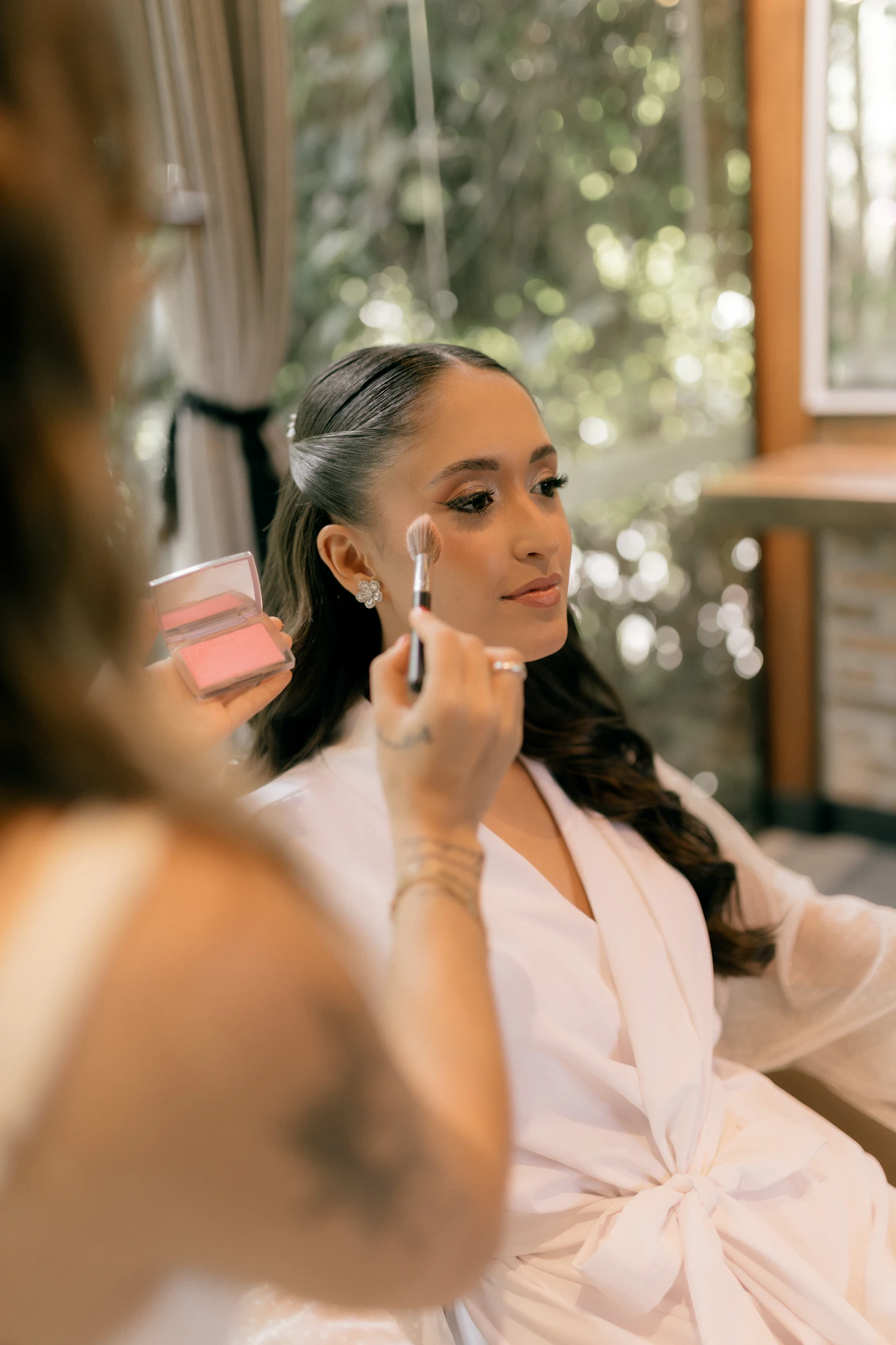 A makeup artist applies blush to a woman's face.