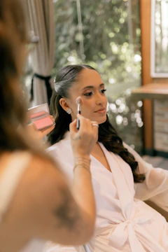 A makeup artist applies blush to a woman's face.