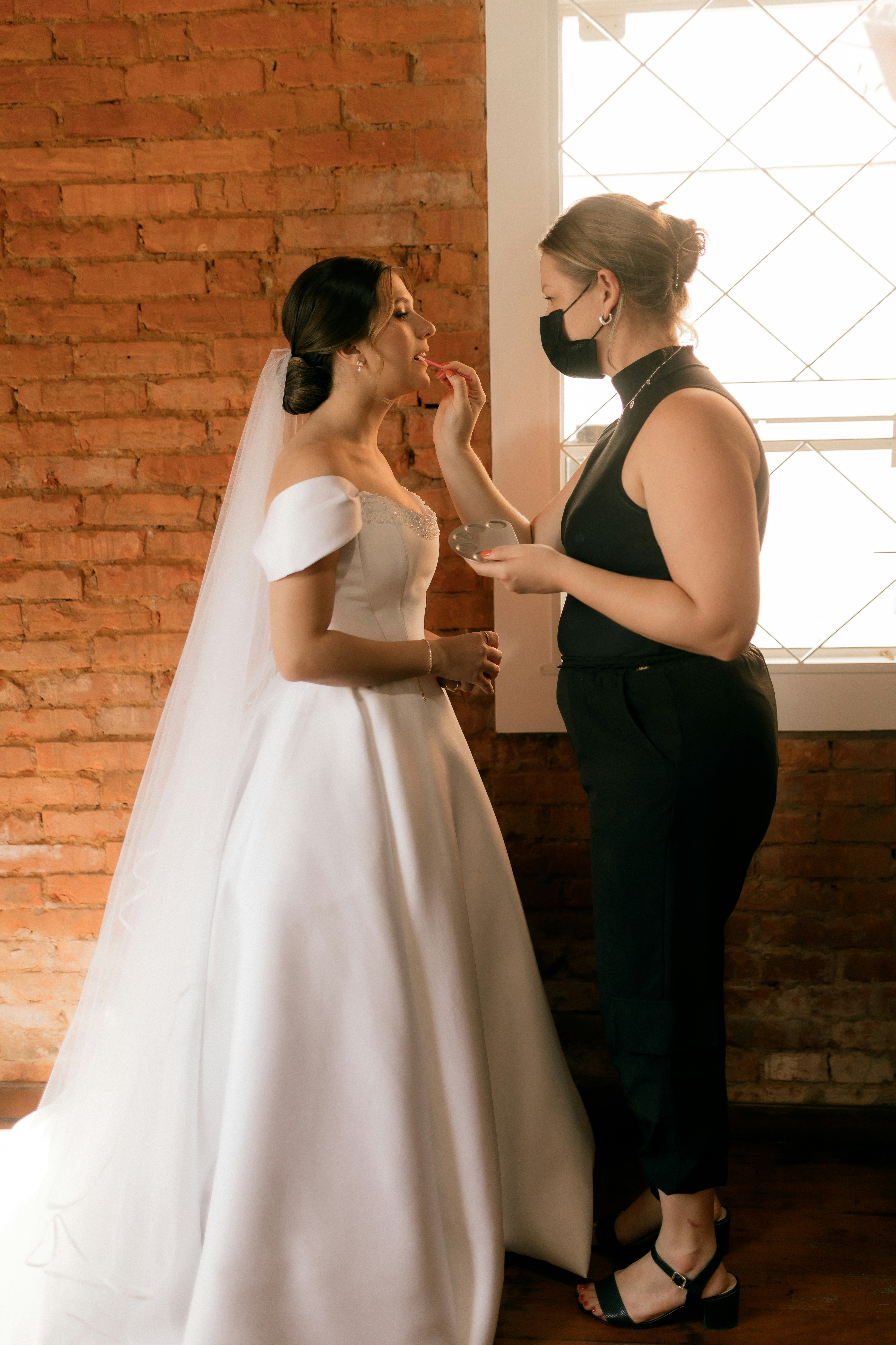 Die Braut lässt sich von einer Maskenbildnerin schminken.