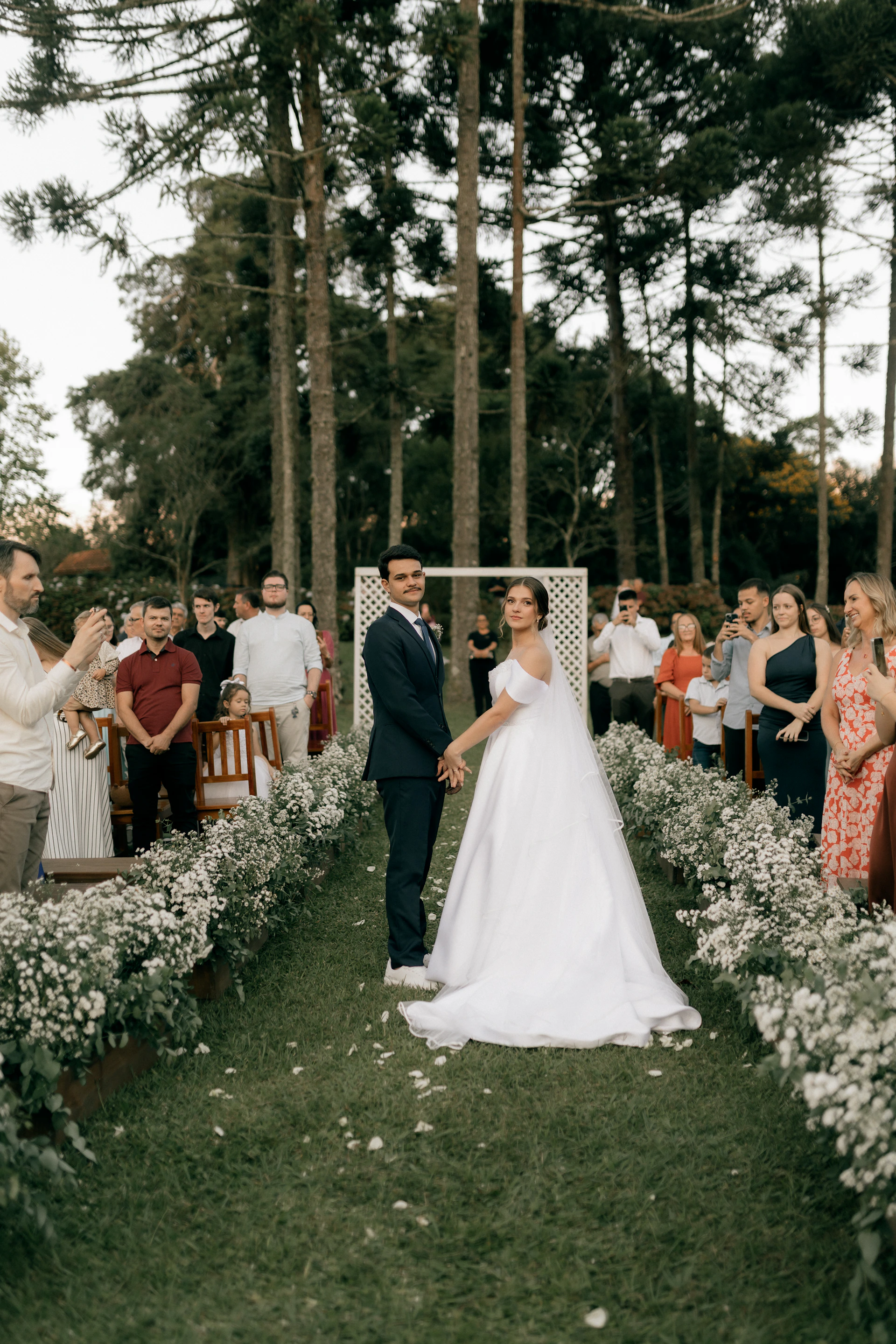 A bride and groom stand at an outdoor wedding ceremony.