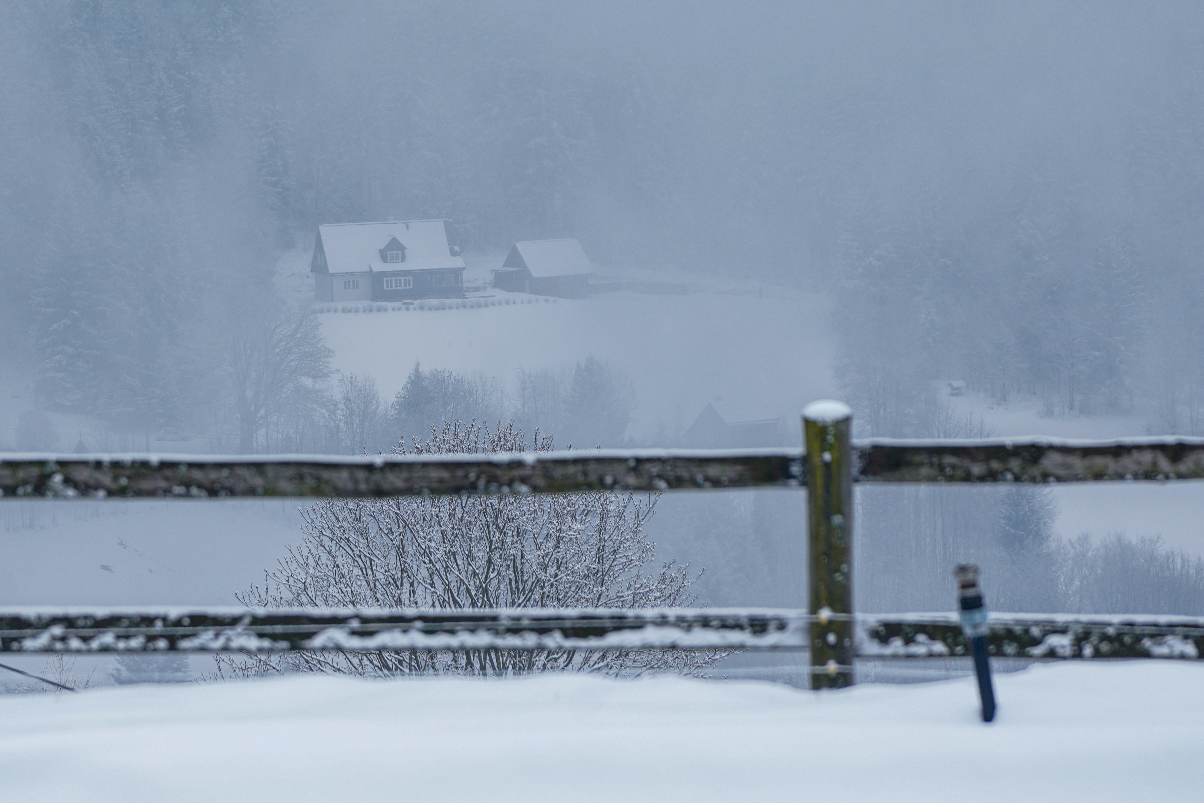 Wooden fence in snowy landscape with distant houses