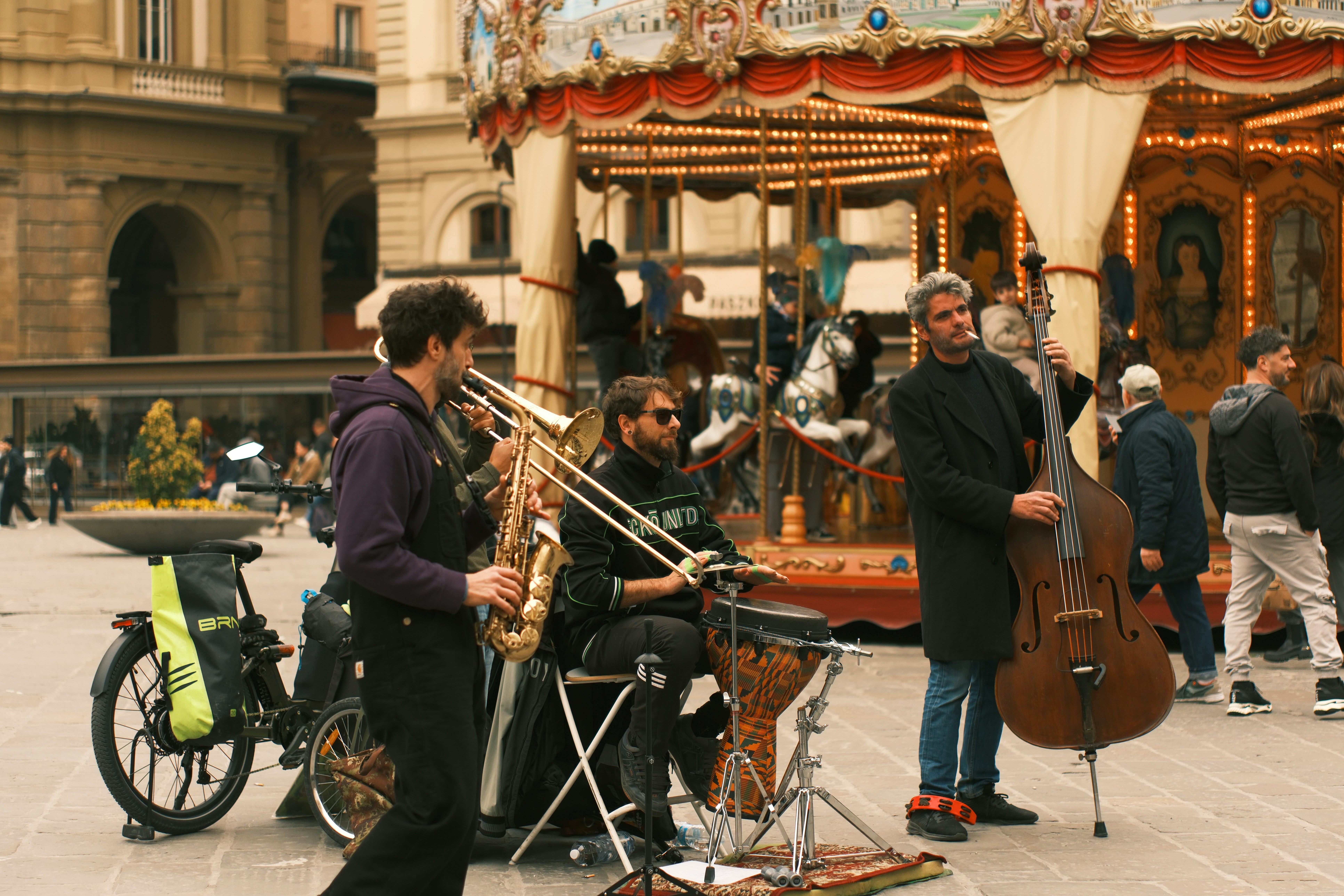 Musicians playing instruments in front of a carousel.
