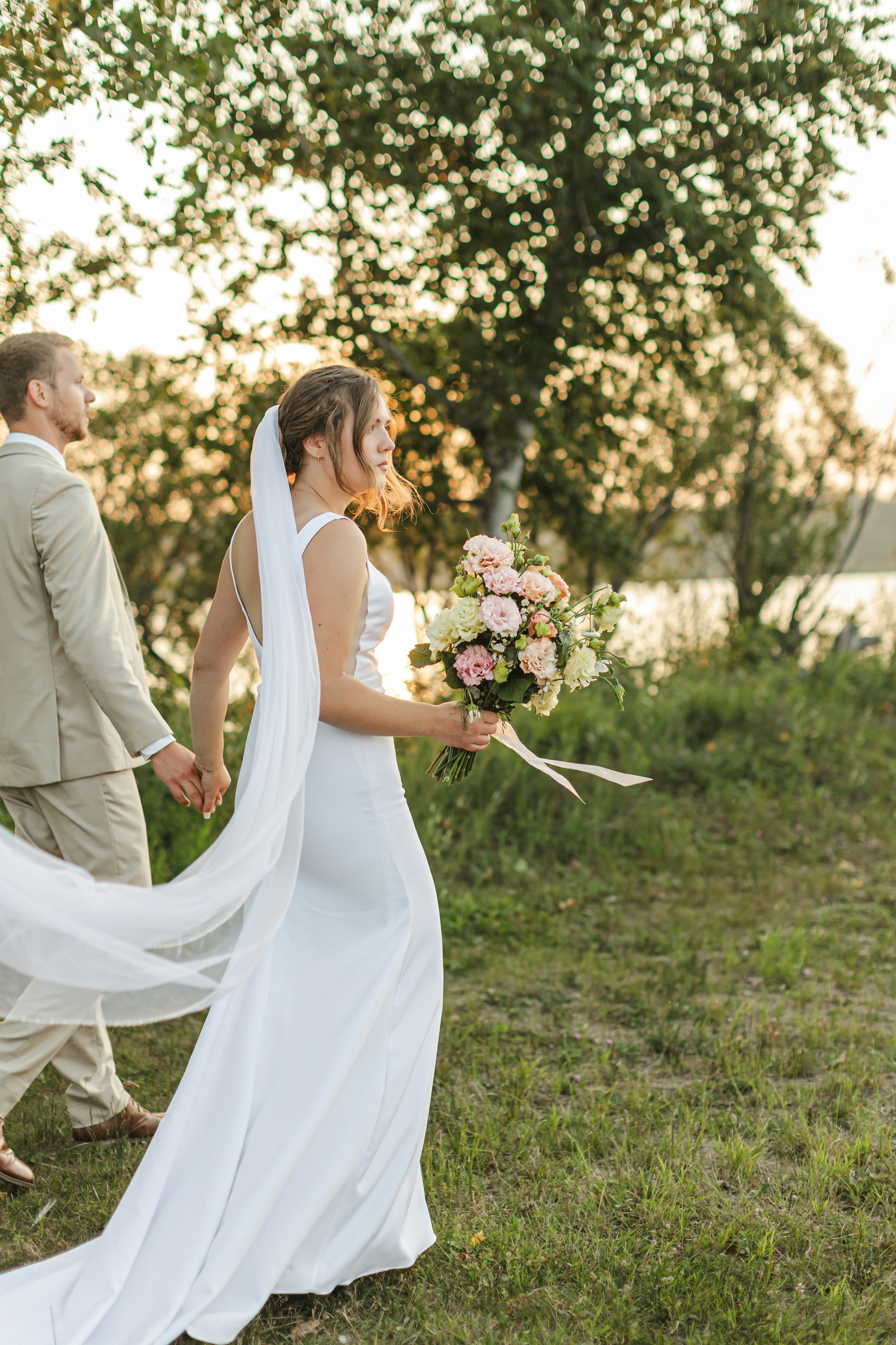 Bride and groom walking hand-in-hand at sunset
